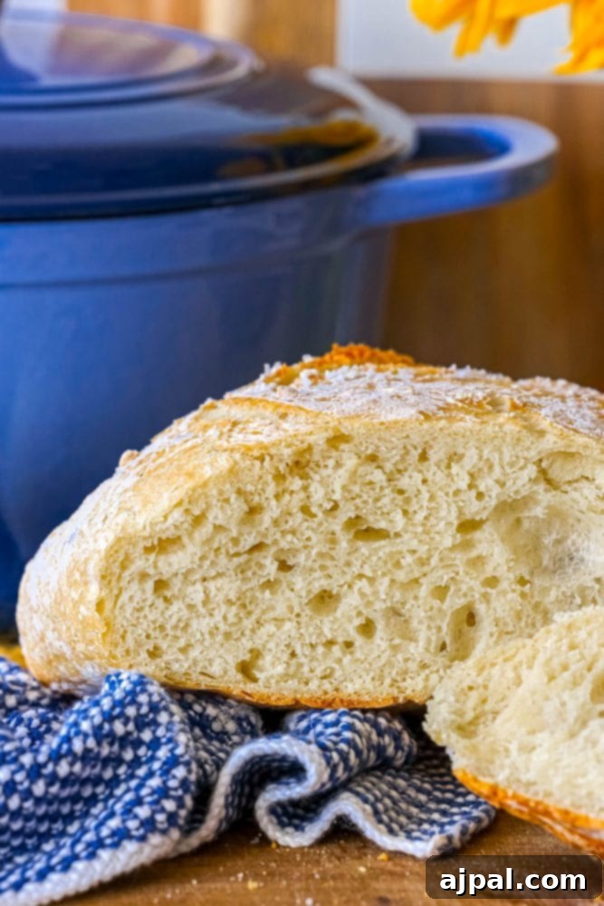 Effortless No-Knead Bread 18 A beautiful loaf of no-knead bread, perfectly browned, next to a blue pot on a cutting board, ready for serving.
