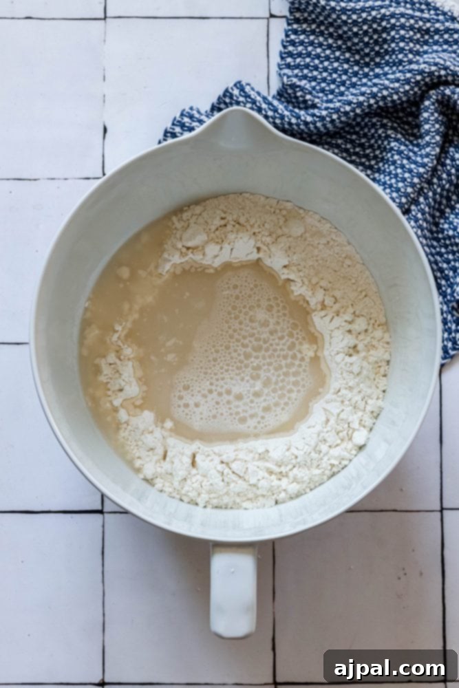 Effortless No-Knead Bread 9 Lukewarm water, mixed with yeast, being poured into the well of flour in a mixing bowl.