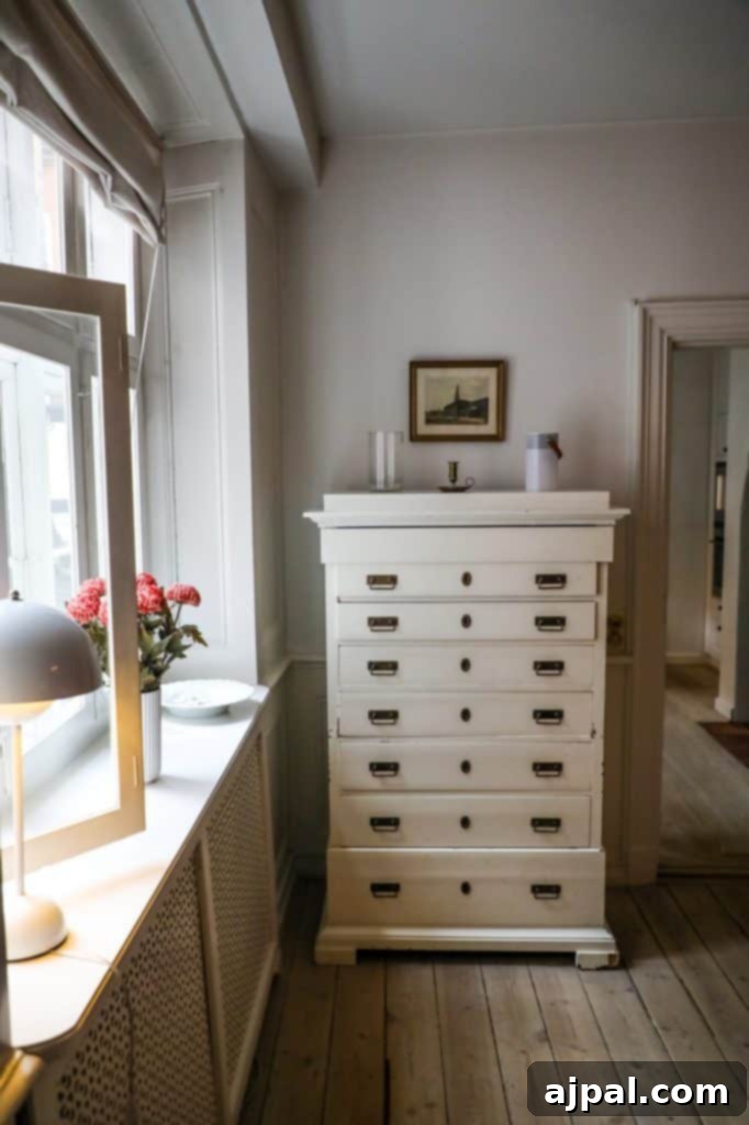 Paper Island Copenhagen Urban Oasis 14 A stylish white dresser in a room with a window overlooking the enchanting Tivoli Gardens, highlighting the cozy and well-appointed Airbnb in Copenhagen.