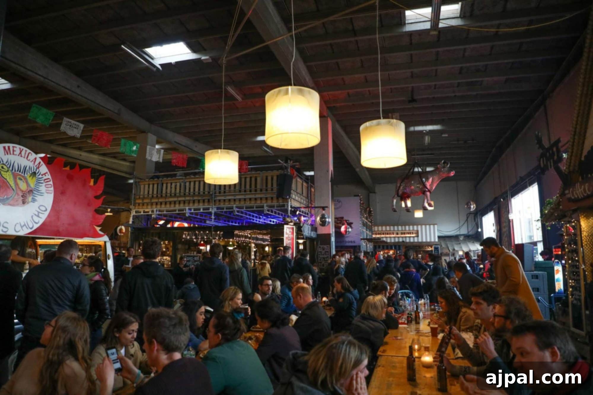 Paper Island Copenhagen Urban Oasis 5 A vibrant interior shot of Copenhagen Street Food on Paper Island, showing a diverse crowd enjoying food and drinks in the bustling hall.