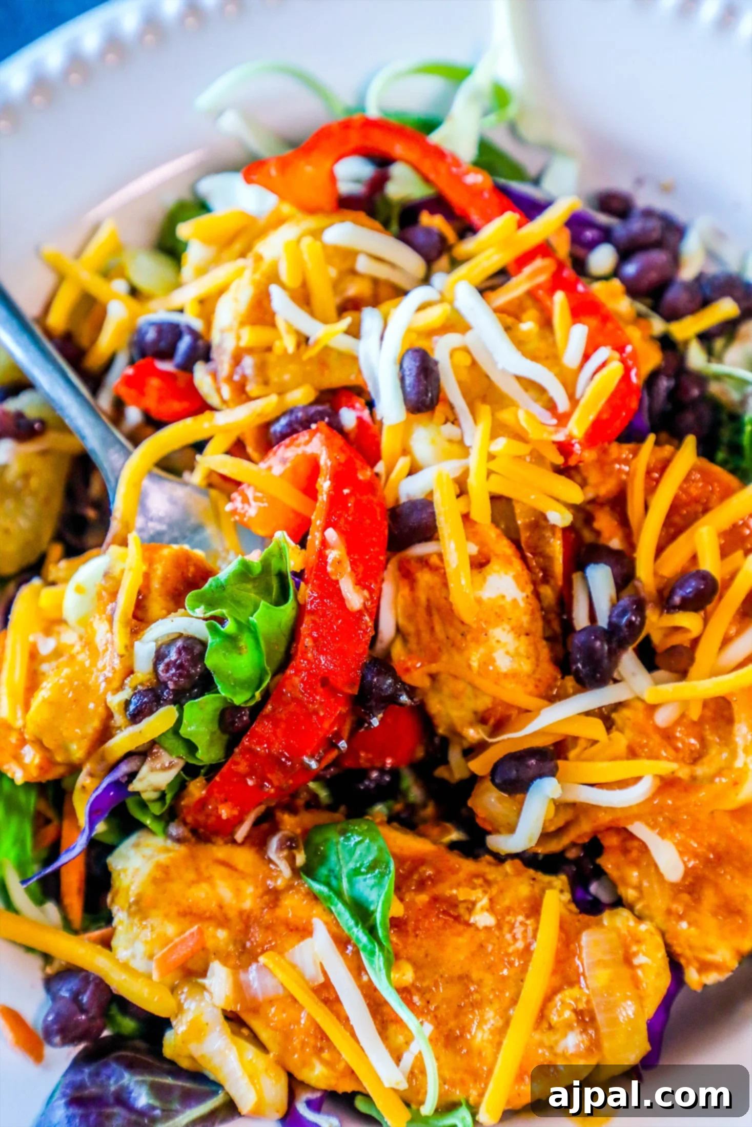 One Pan Baked Chicken Fajitas 5 A plate of chicken fajita salad with black beans, cheese, lettuce, and lime