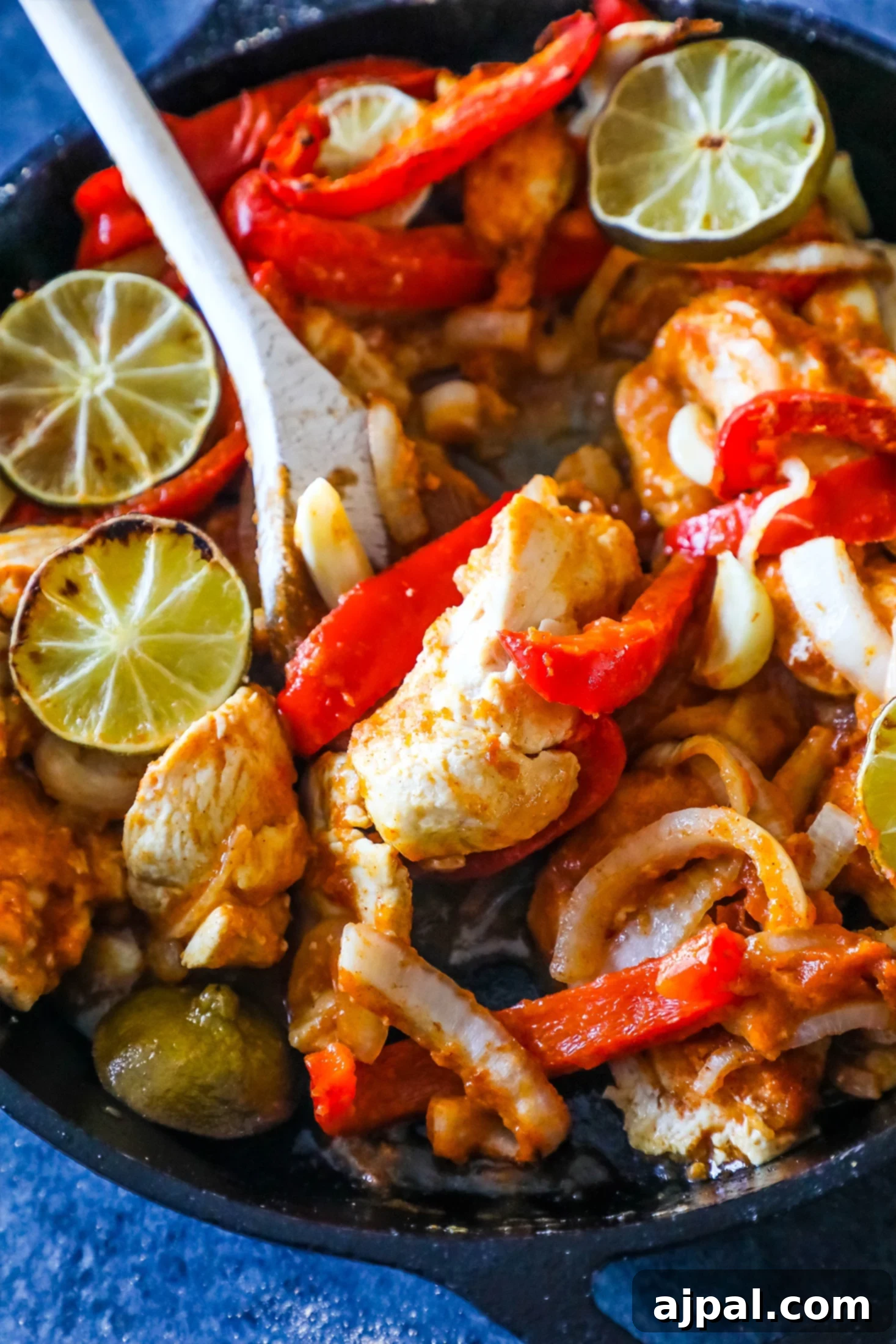 One Pan Baked Chicken Fajitas 4 Chicken, bell peppers, and lime in a pan with a serving spoon