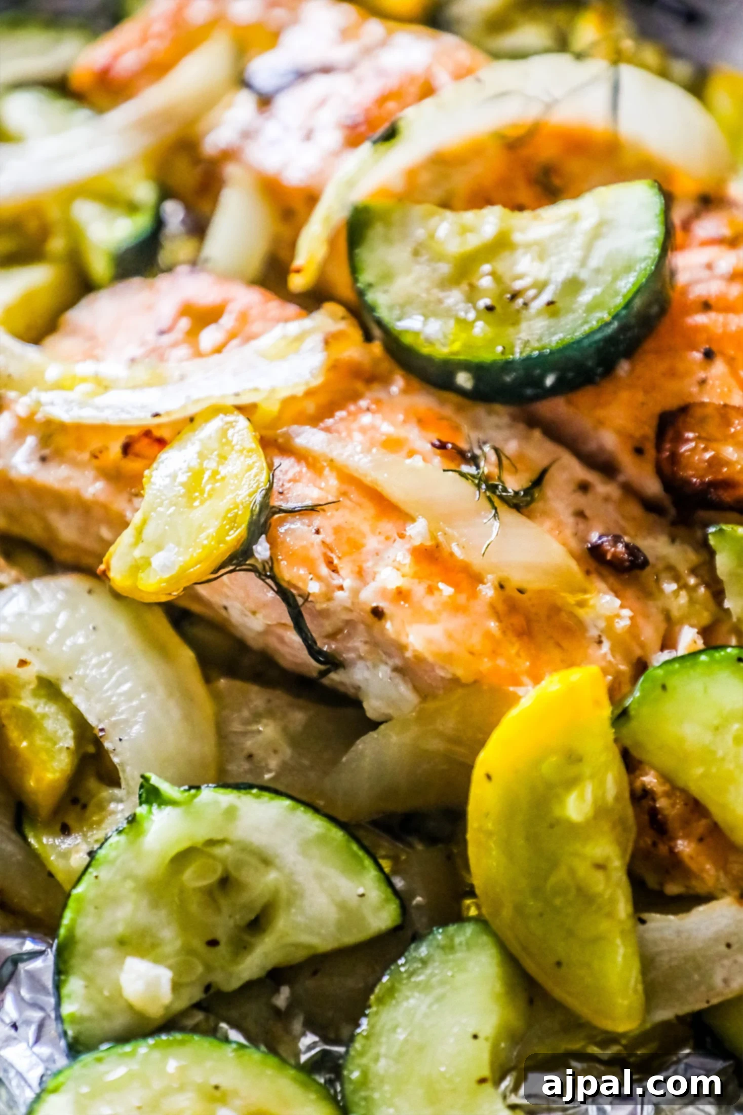 Garlic Herb Salmon and Zucchini Foil Packs 4 Three individual garlic herb salmon and zucchini foil packets, neatly folded and ready for baking, displaying fresh dill, garlic, and seasoning.