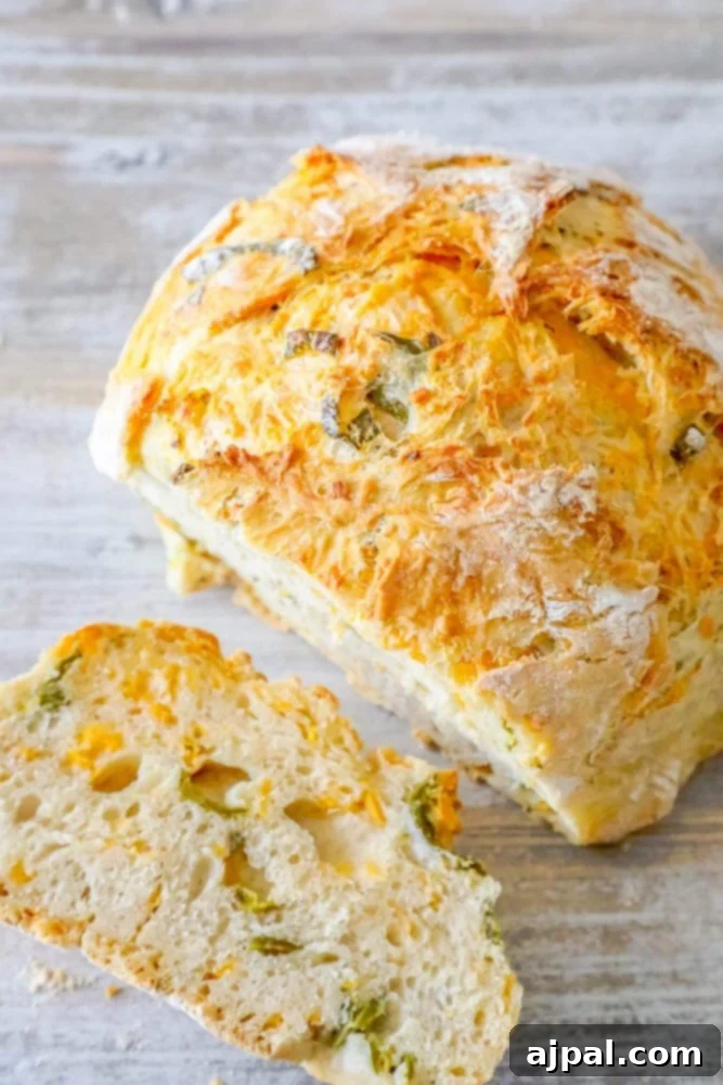 Sliced no-knead jalapeño cheddar bread on a cutting board, showcasing cheese and jalapeño pieces