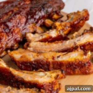 Perfectly Tender Oven Baked Ribs 13 picture of ribs slathered in sauce on a wood platter