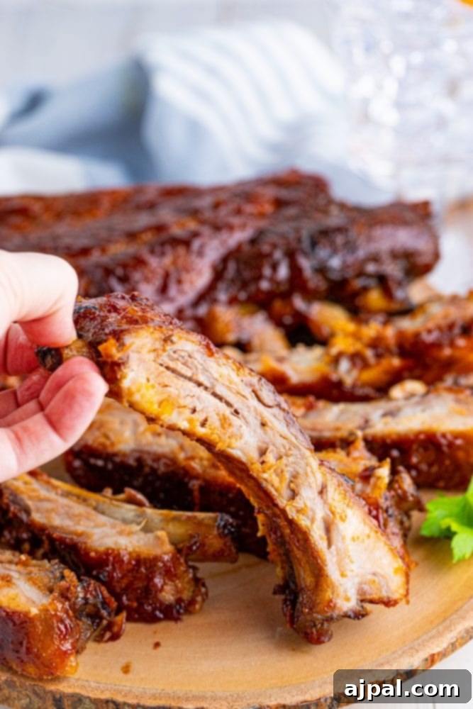 Perfectly Tender Oven Baked Ribs 4 A serving of delectable baked BBQ ribs, glistening with sauce, presented beautifully on a wooden plate.