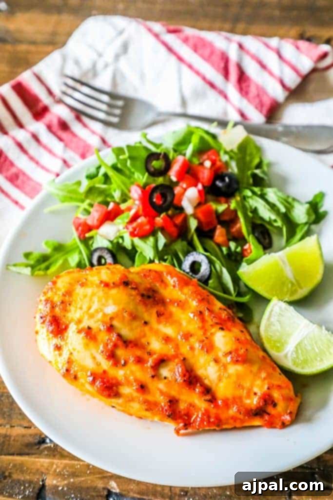 Pimento Infused Roast Chicken 2 Tender oven-roasted pimento chicken breast served alongside a fresh salad with olives and tomatoes, garnished with bright lime wedges.