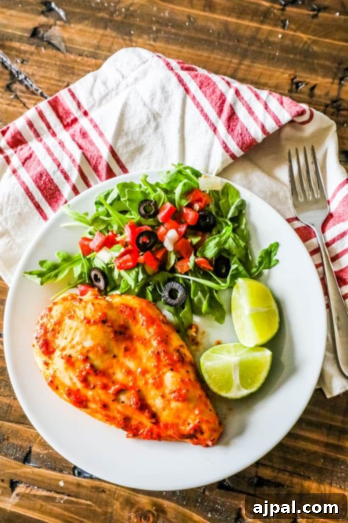 Pimento Infused Roast Chicken 7 A plate with oven-roasted chicken breasts and a salad topped with pimento, garnished with lime.
