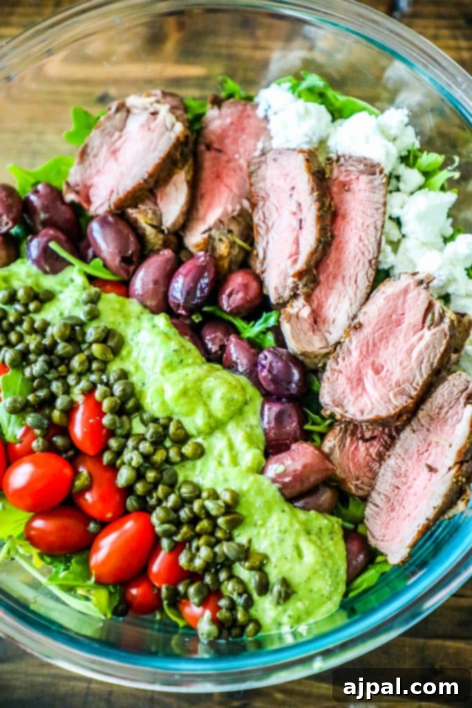 A delectable creamy steak salad presented in a glass bowl, garnished with fresh tomatoes and herbs, highlighting the rich flavors and inviting textures.