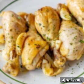 A plate of Greek chicken drumsticks garnished with fresh herbs and garlic cloves offers a savory Mediterranean delight.
