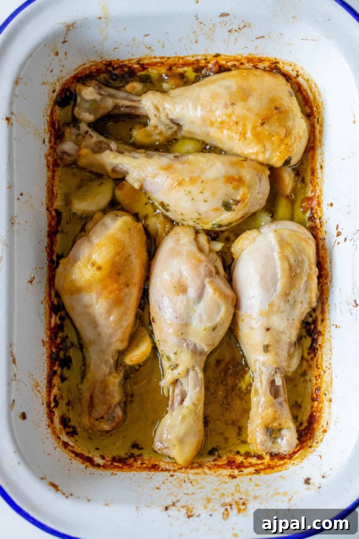 Zesty Greek Chicken Drumsticks 8 Five Greek chicken drumsticks, perfectly roasted, rest in a white baking dish.