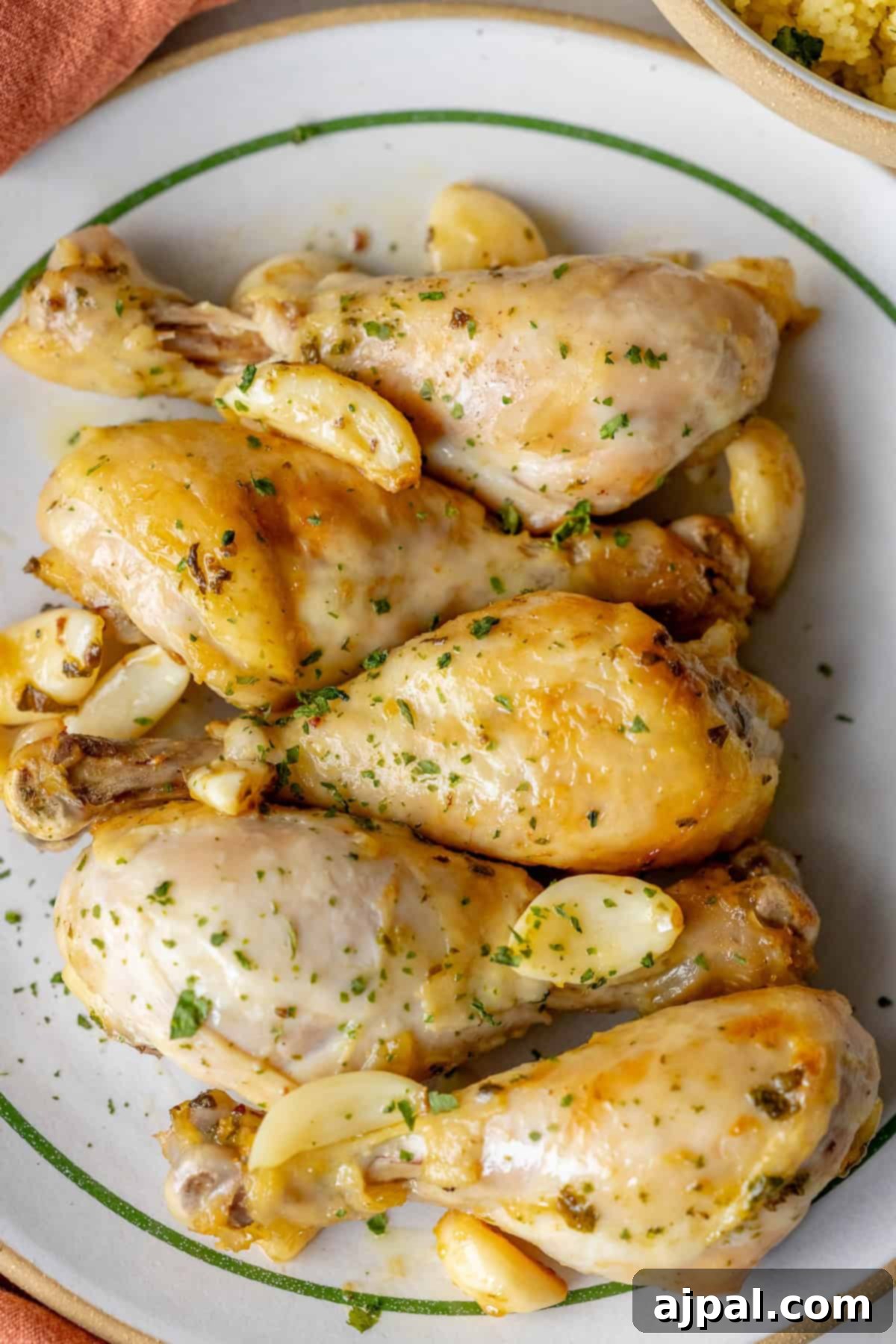 Zesty Greek Chicken Drumsticks 9 A plate of Greek chicken drumsticks garnished with aromatic herbs and garlic cloves.