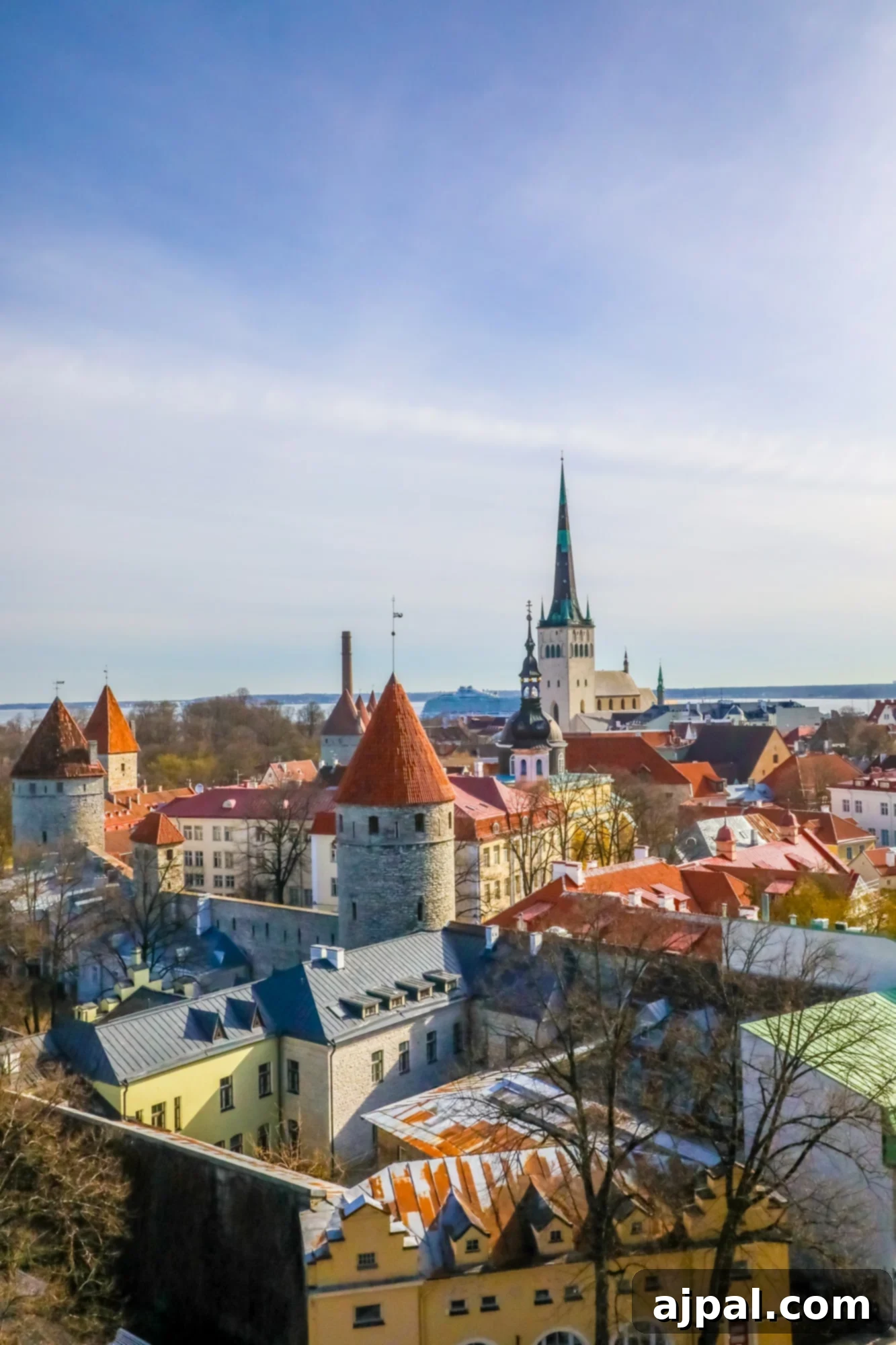 A scenic aerial view of Tallinn, Estonia's Old Town, showcasing its red rooftops, ancient walls, and the distant Baltic Sea horizon.