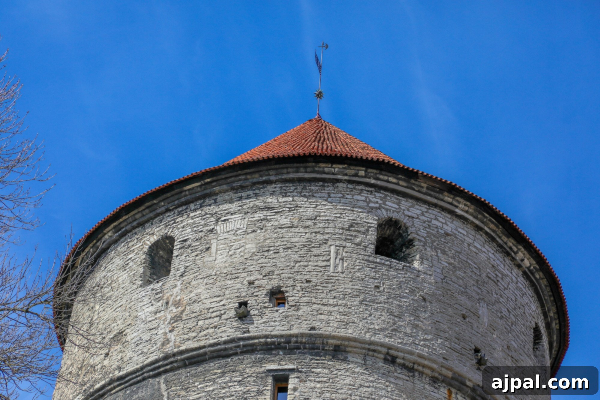 A majestic medieval stone tower in Tallinn, Estonia, silhouetted against a clear blue sky, evoking centuries of history.