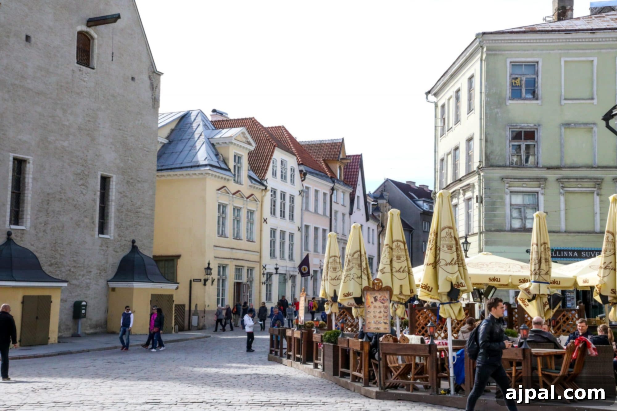 A charming cobblestone street in Tallinn's City Square, lined with cafes offering outdoor seating under colorful umbrellas.