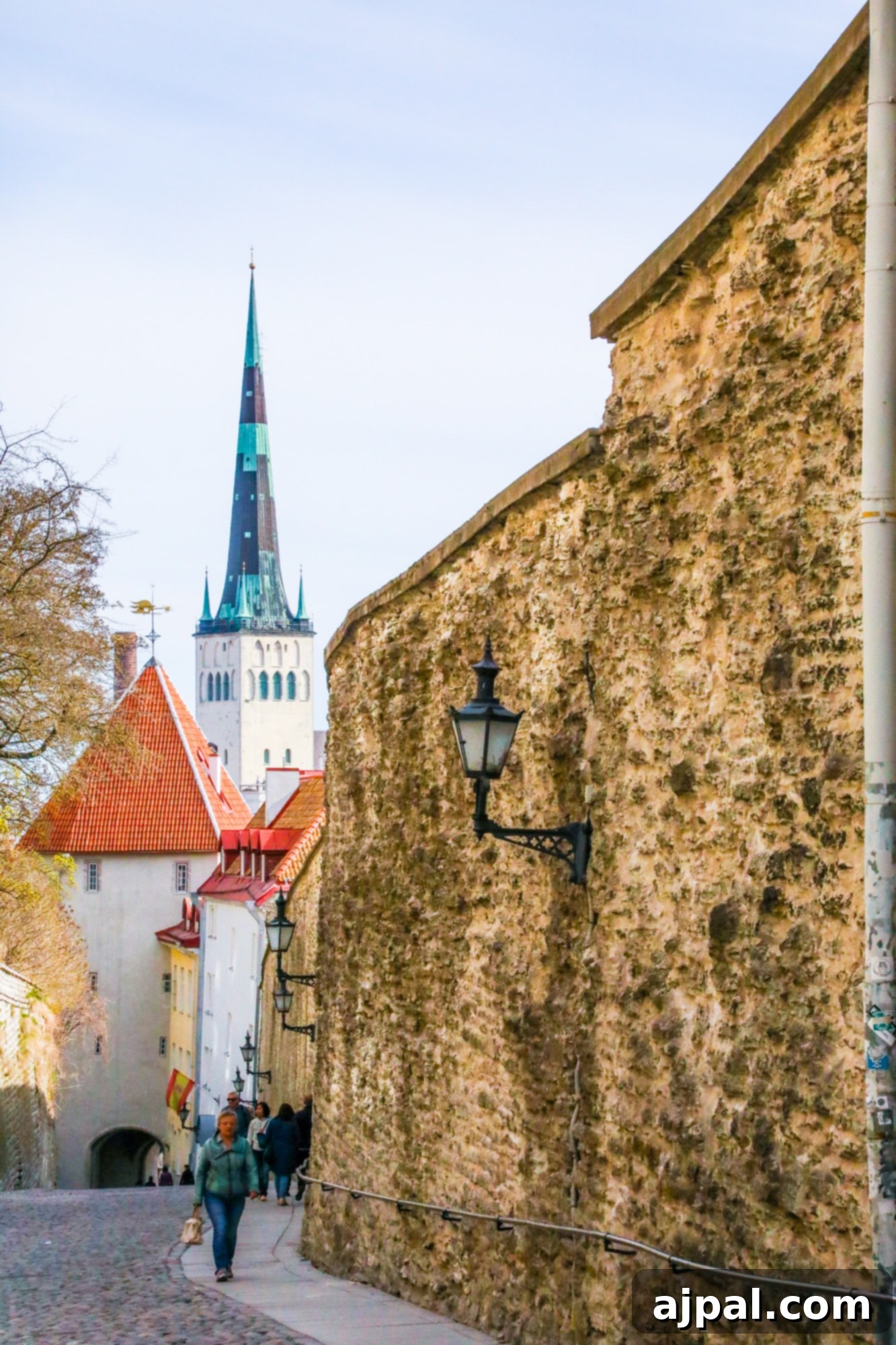 A picturesque cobblestone street in Tallinn, Estonia's Old Town, flanked by historic buildings and leading towards a church steeple.
