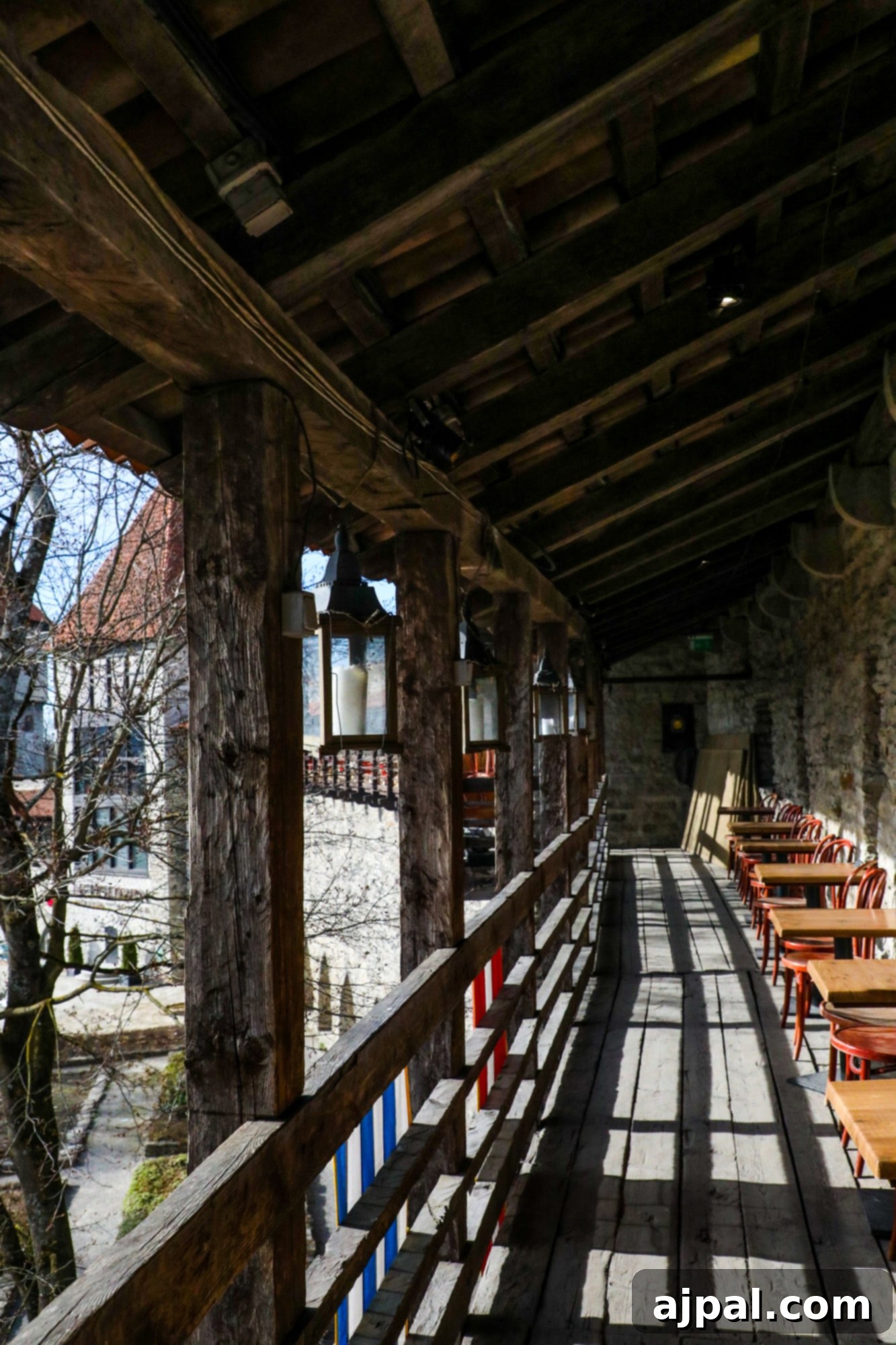 The exterior of Cafe Dannebrog in Tallinn, Estonia, showing a wooden walkway and outdoor seating in front of a historic stone tower.