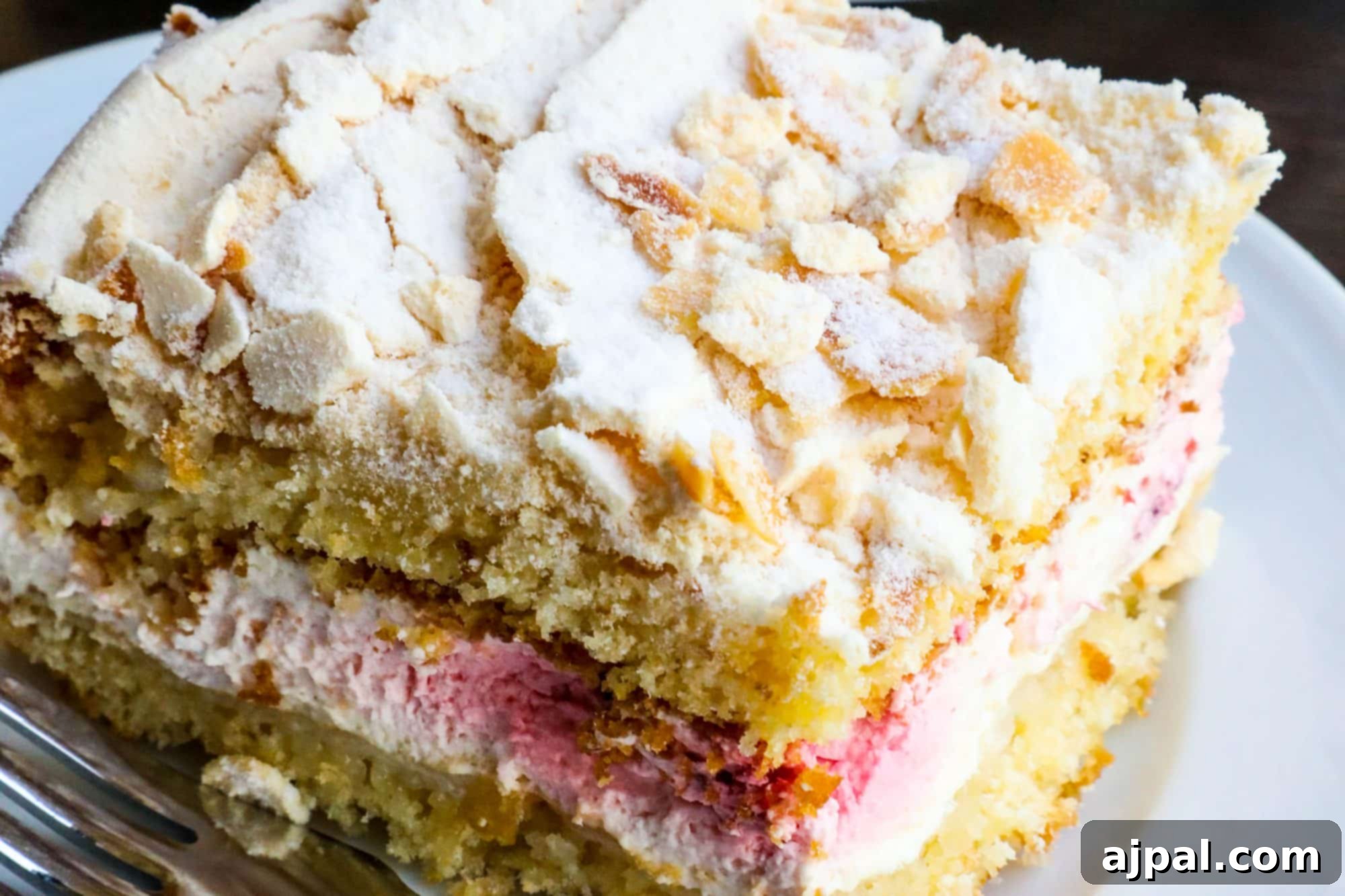 A delightful slice of Brita Cake, a traditional Finnish cake with strawberries and meringue, served on a white plate with a fork.