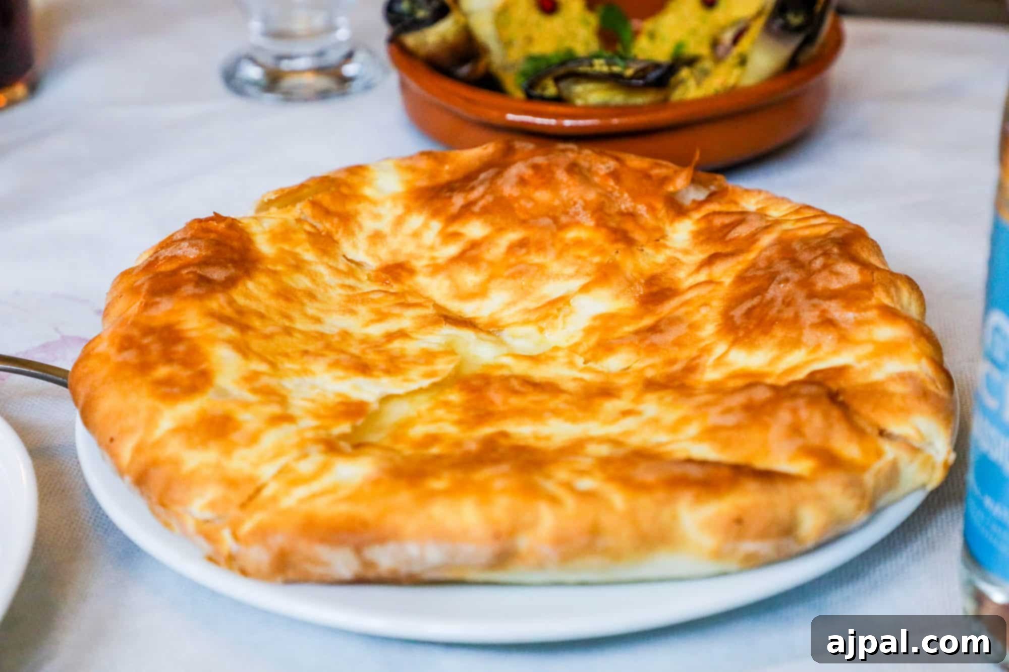 A vibrant Khachapuri, a Georgian cheese bread resembling a pizza, served alongside a glass of red wine.
