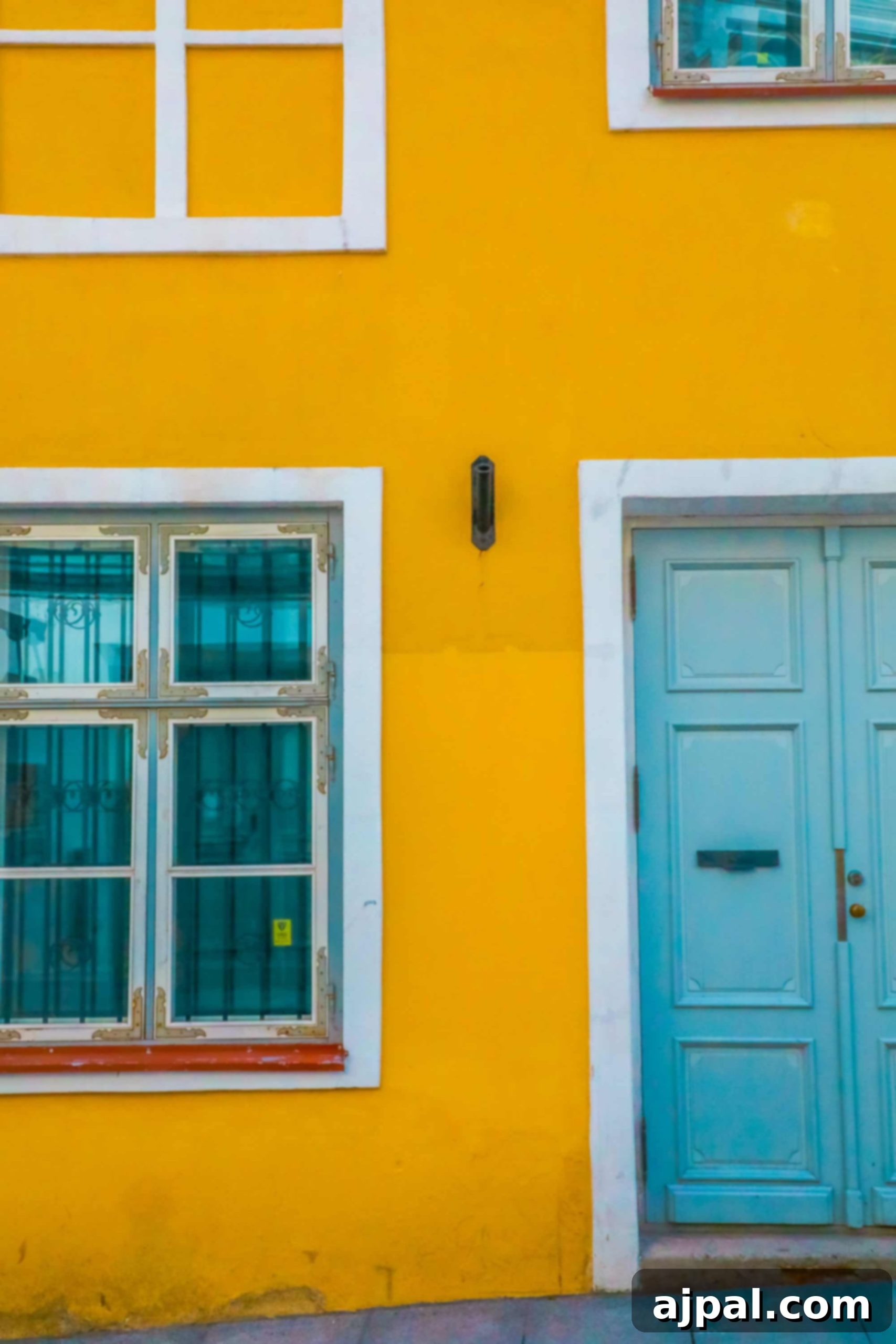 A charming yellow house in Tallinn, Estonia, featuring a vibrant blue door and windows, adding a splash of color to the historic streets.