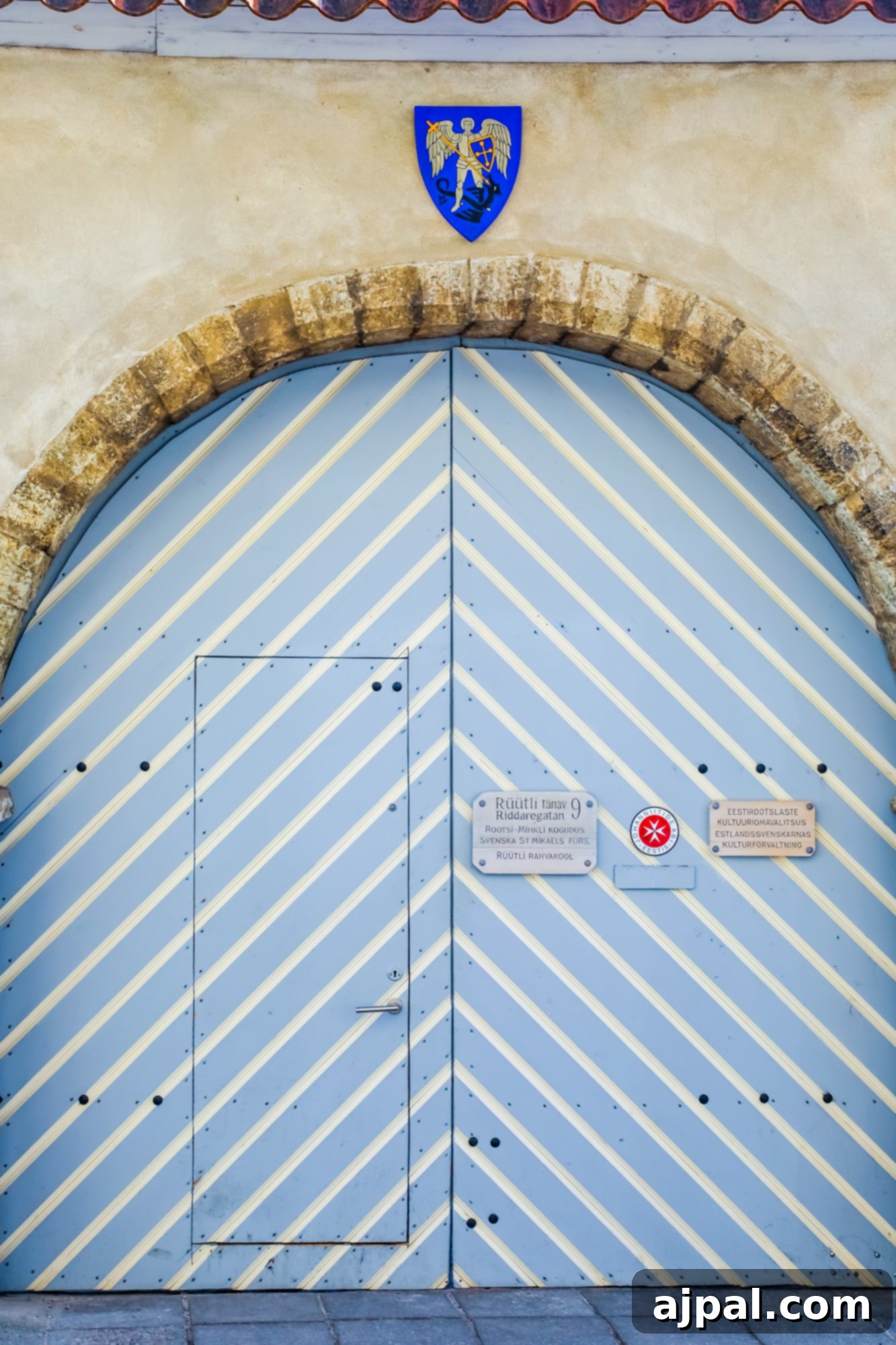 A distinctive blue and white striped door adorned with a decorative sign in Tallinn, Estonia, capturing a unique aspect of the city's charm.