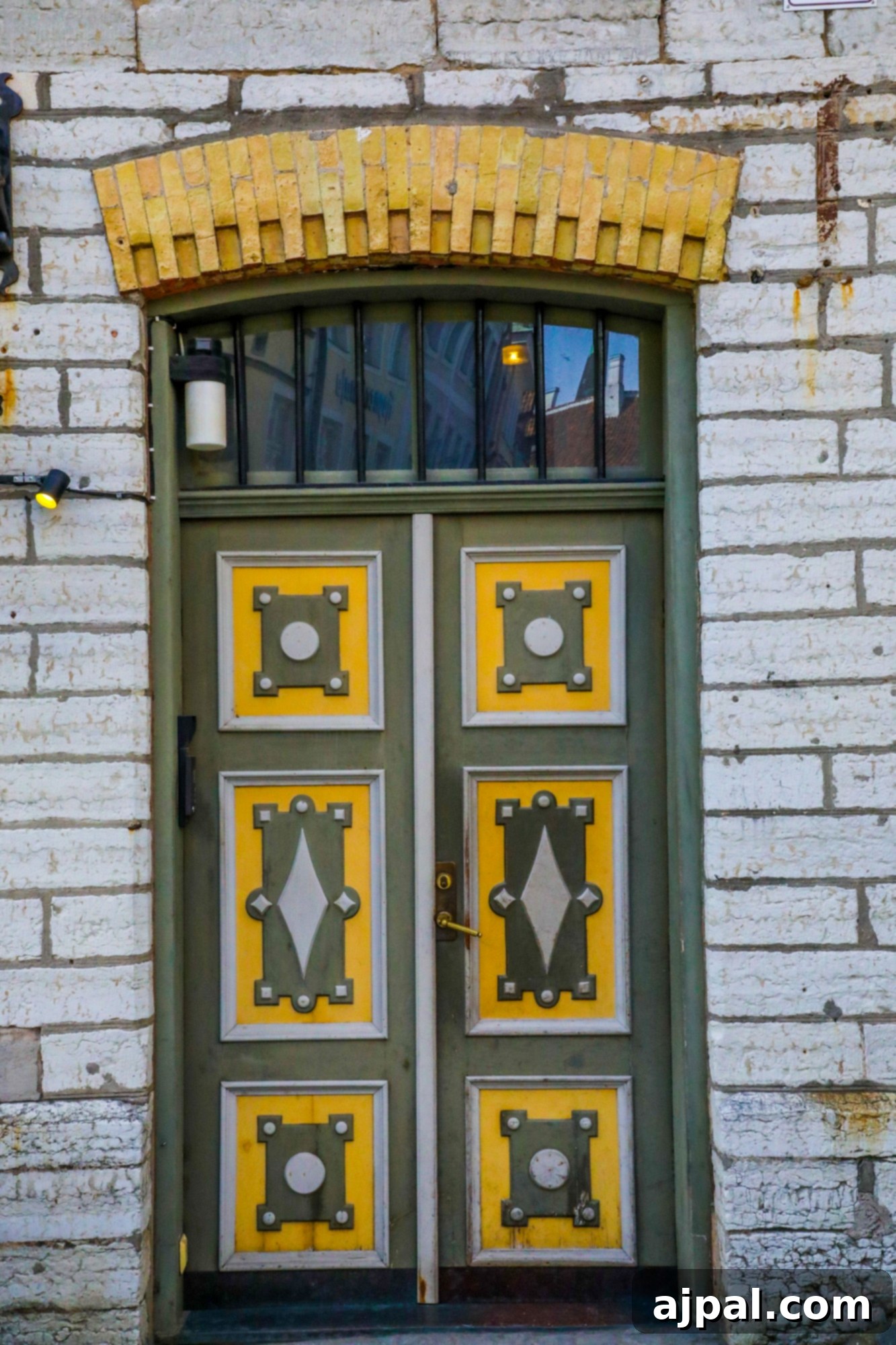 A striking green and yellow painted door set into a brick building in Tallinn, Estonia, showcasing the city's characteristic colorful architecture.