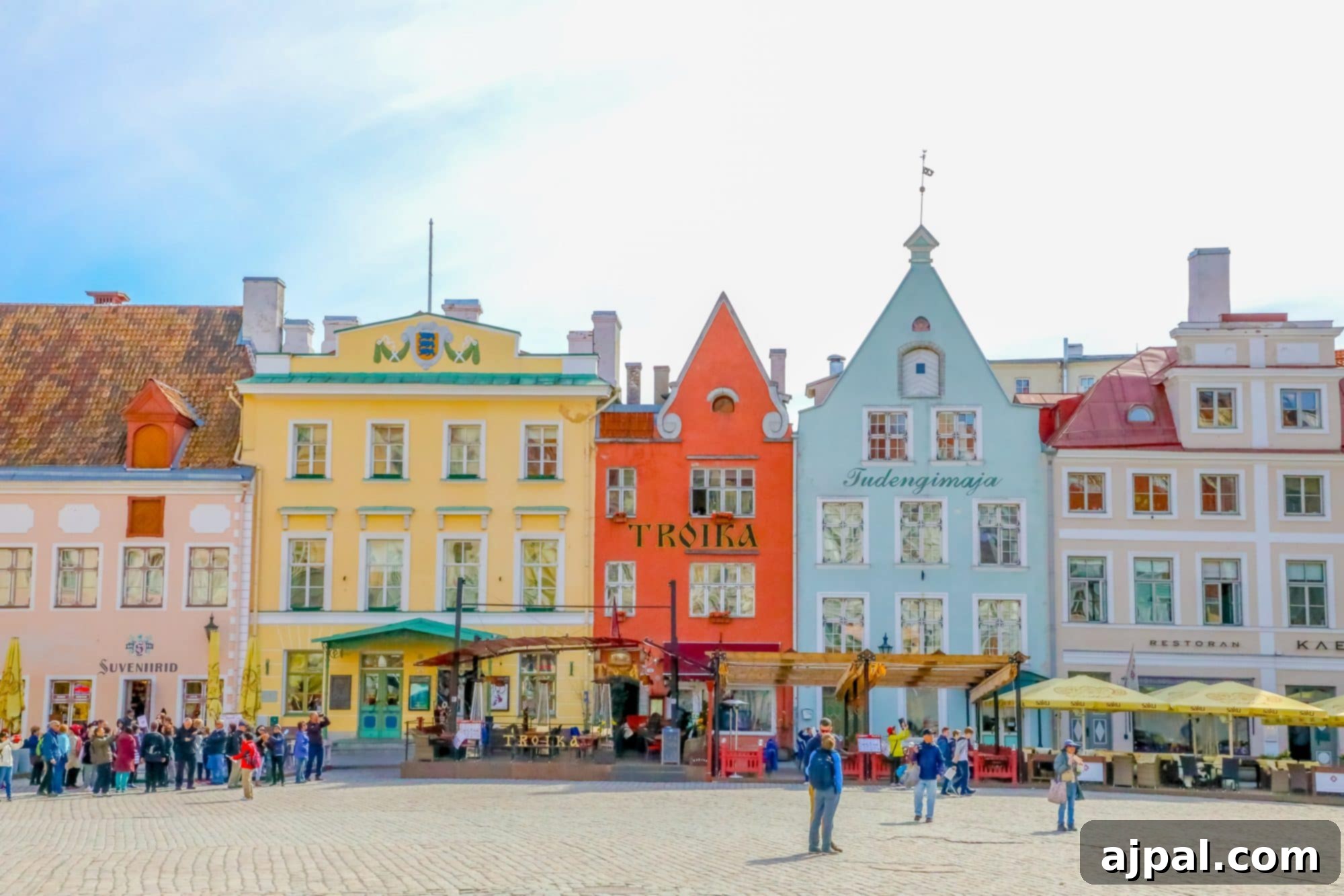 A bustling scene in Tallinn, Estonia's Old Town square, featuring historic buildings, cobblestones, and visitors exploring the area.
