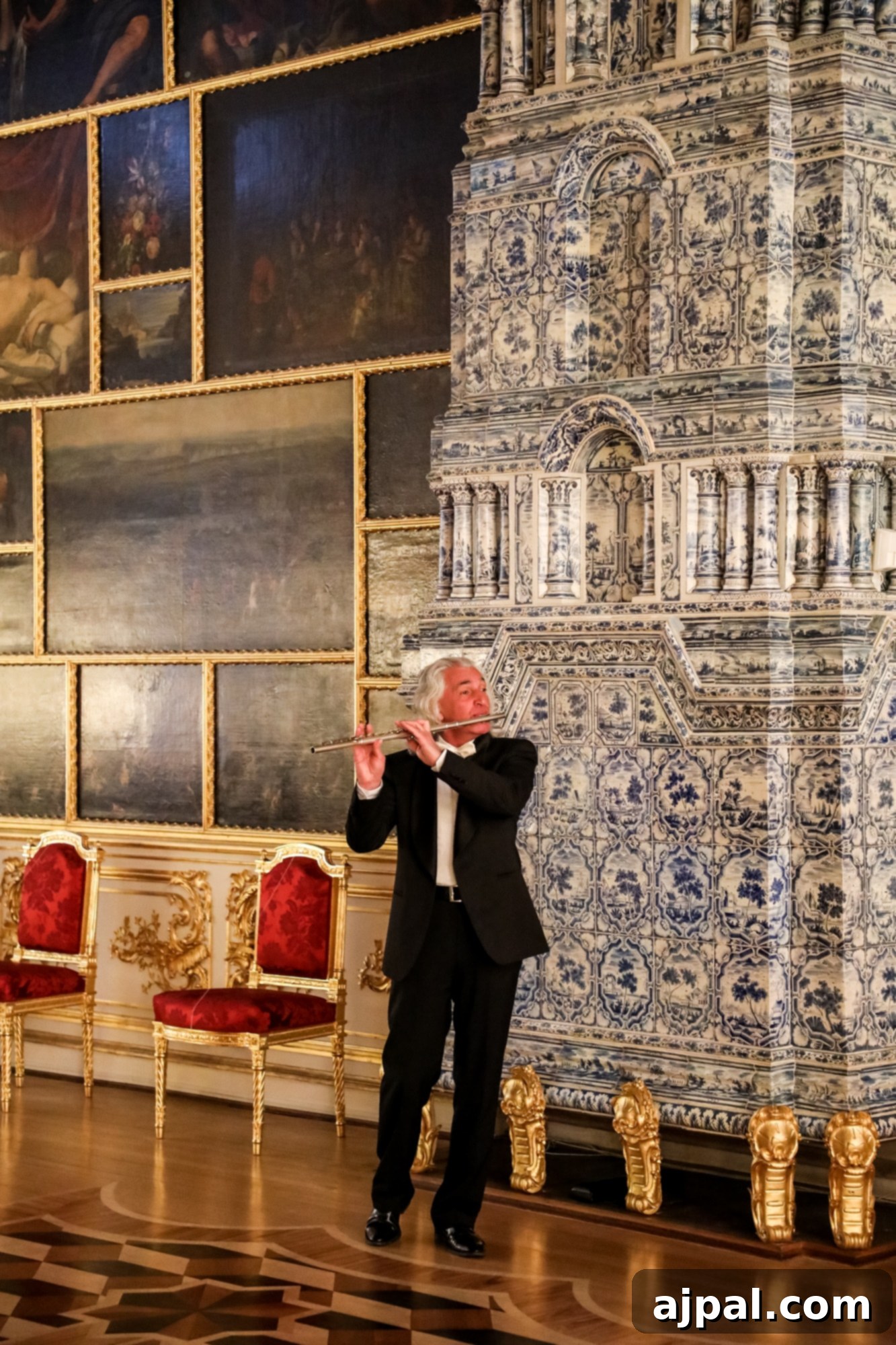 A man in formal attire standing before a grand painting during the Ultimate Saint Petersburg Shore Excursion, featuring a private performance.