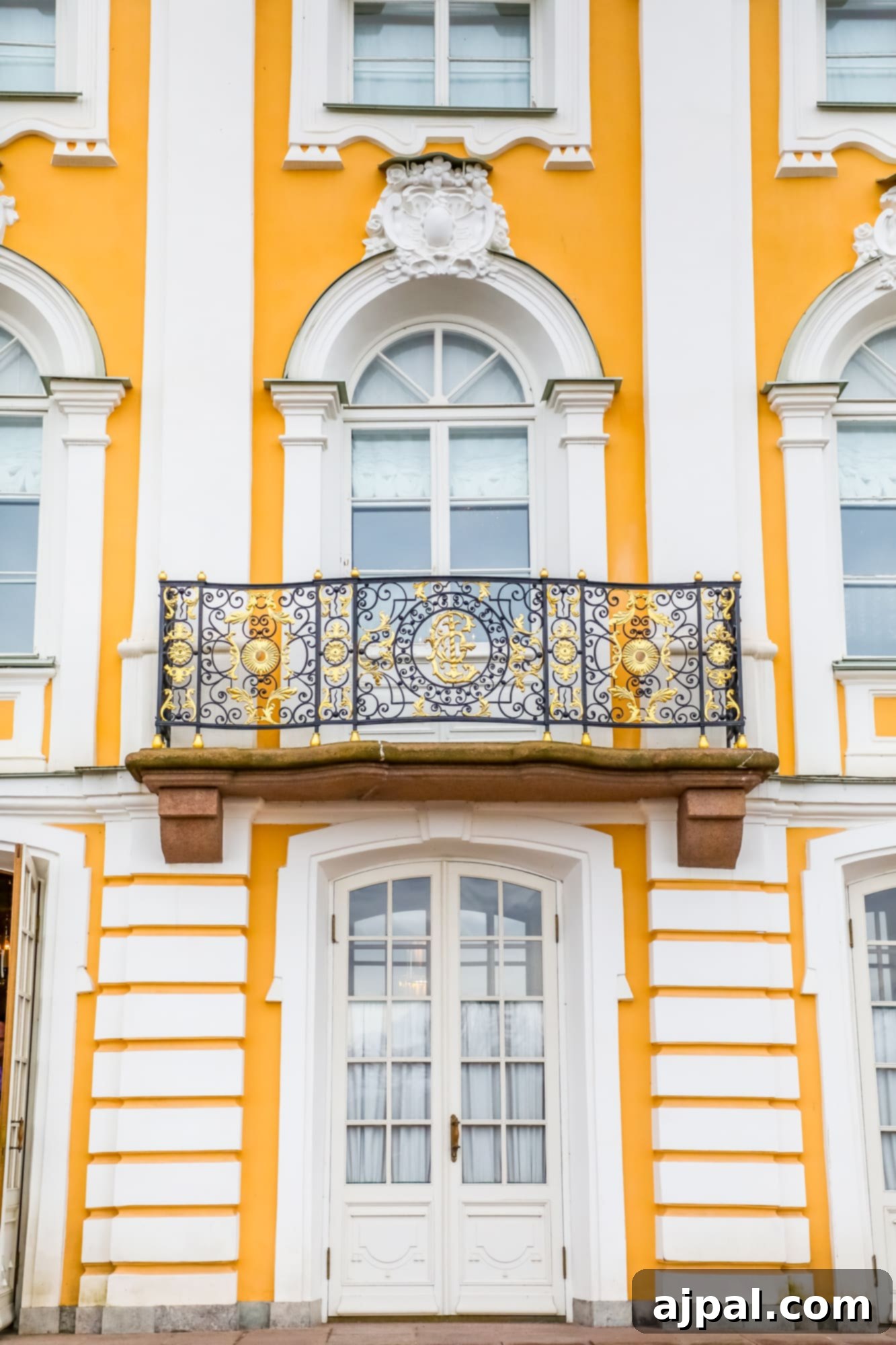 A grand yellow building adorned with ornate balconies and wrought iron railings, capturing the architectural beauty of Peterhof for a Princess Cruises Saint Petersburg shore excursion.