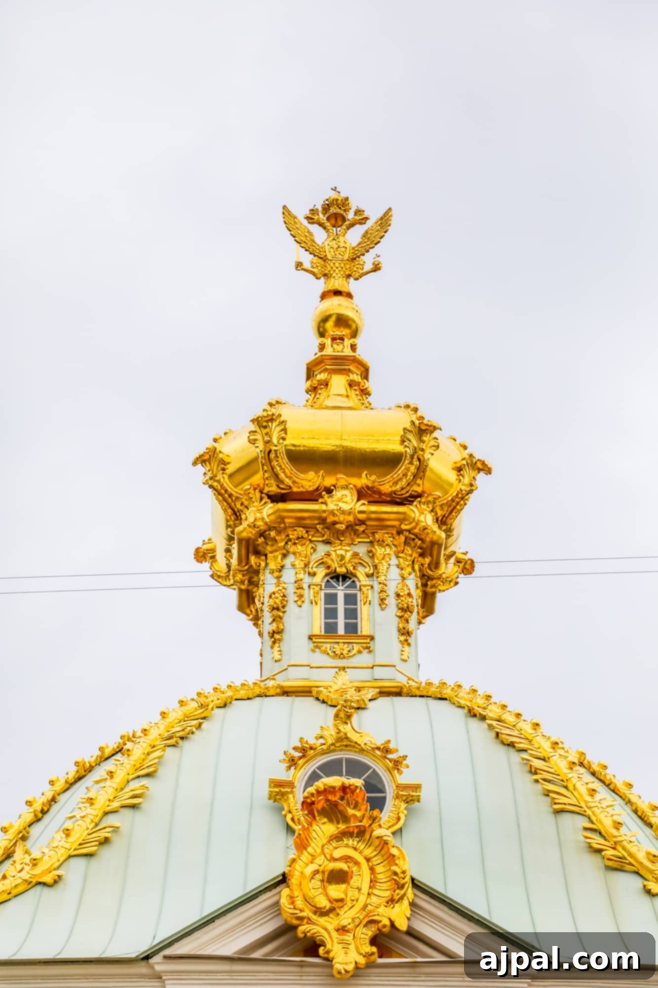 An ornate gold dome atop a majestic building in Saint Petersburg, Russia, likely part of Peterhof Palace.