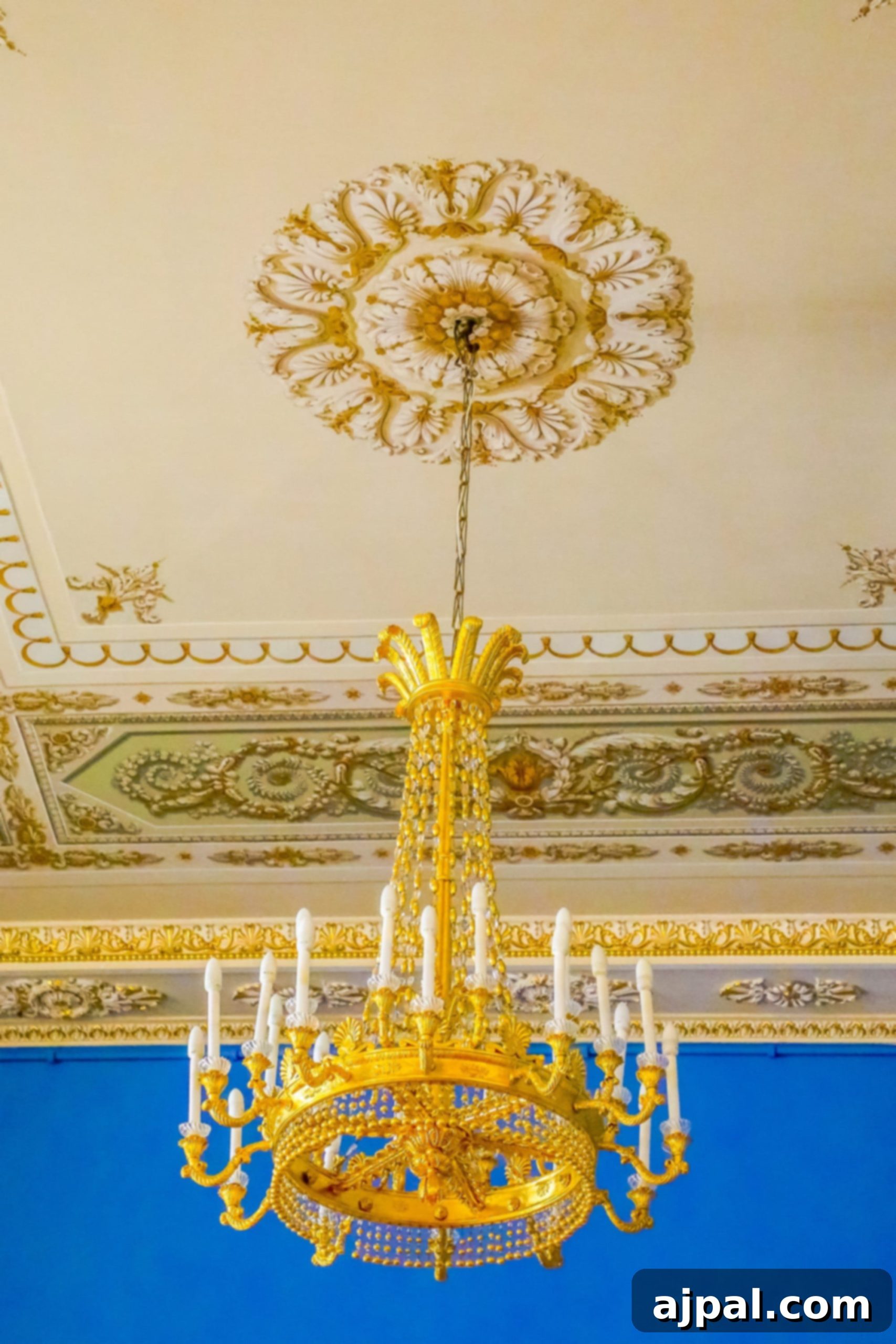 An ornate gold chandelier illuminates a blue room within Yusupov Palace, offering a glimpse into its grandeur during a Saint Petersburg Shore Excursion.
