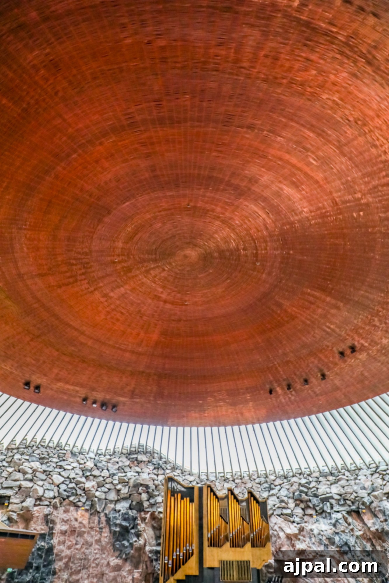 The stunning interior of Temppeliaukio Church, showcasing its unique copper dome ceiling and rock walls.