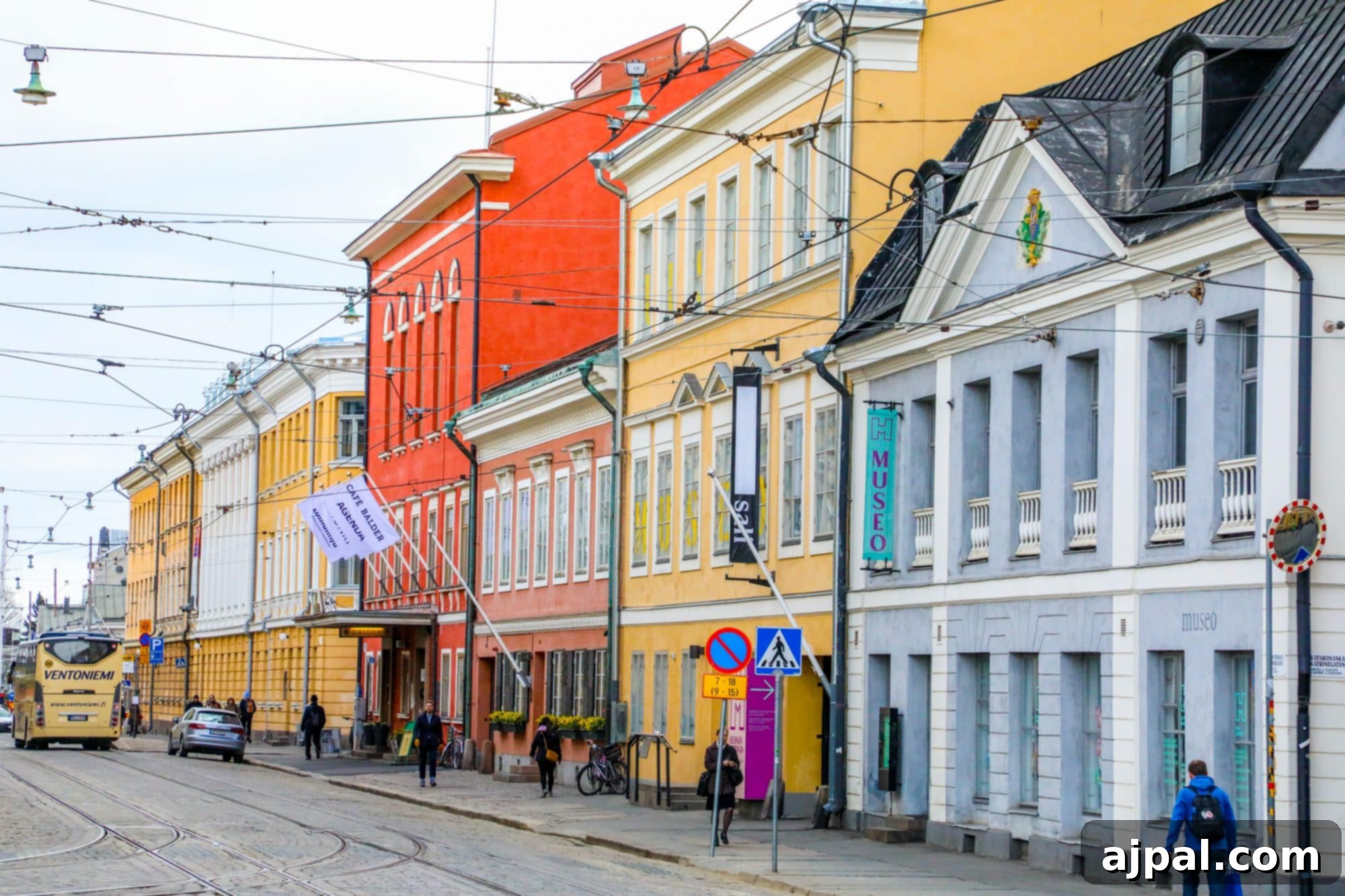 A colorful tram travels down a vibrant street lined with brightly painted buildings in Helsinki.