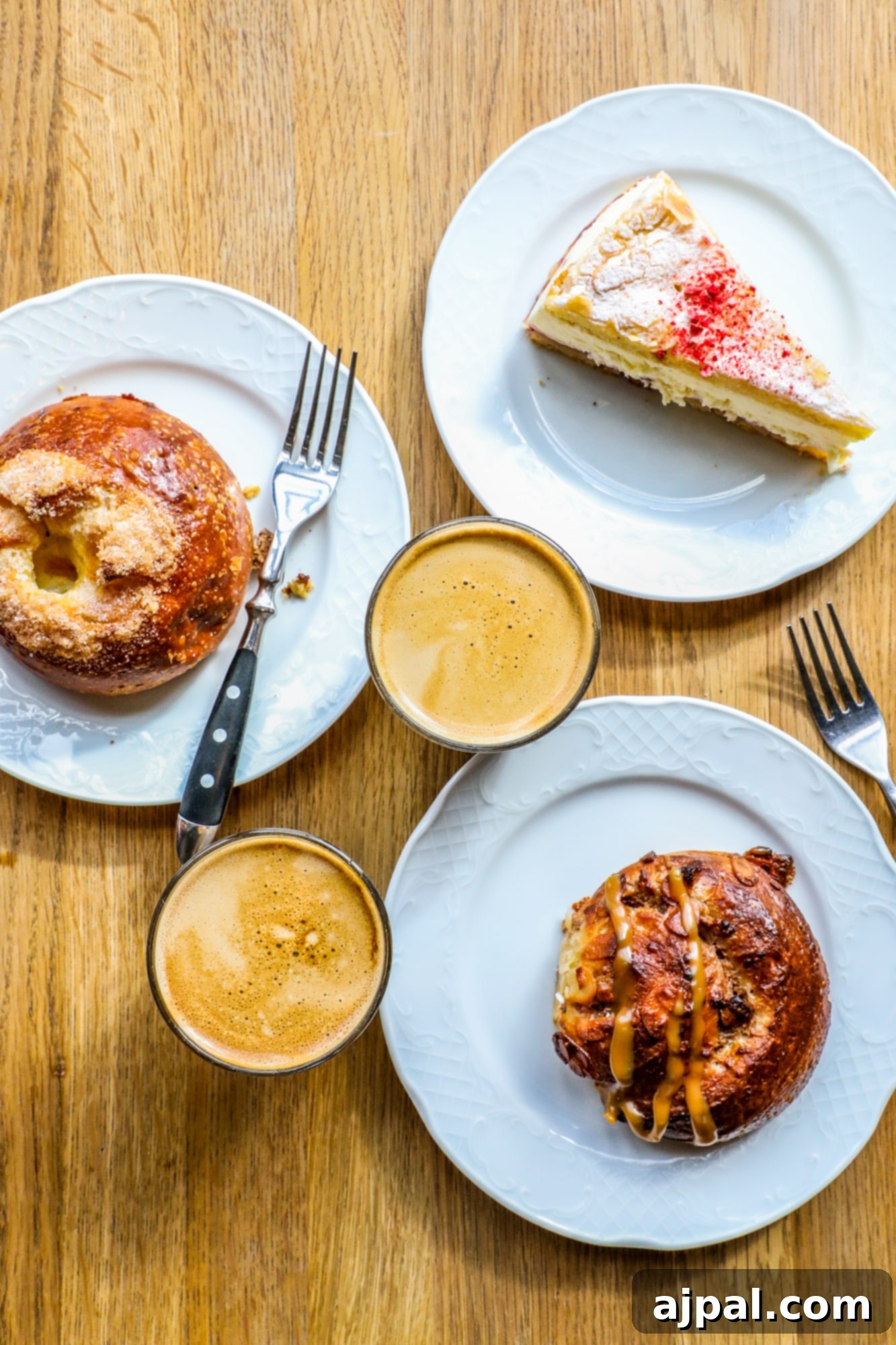 Three plates of delicious pastries and coffee from Story Cafe sit on a rustic wooden table in Helsinki.