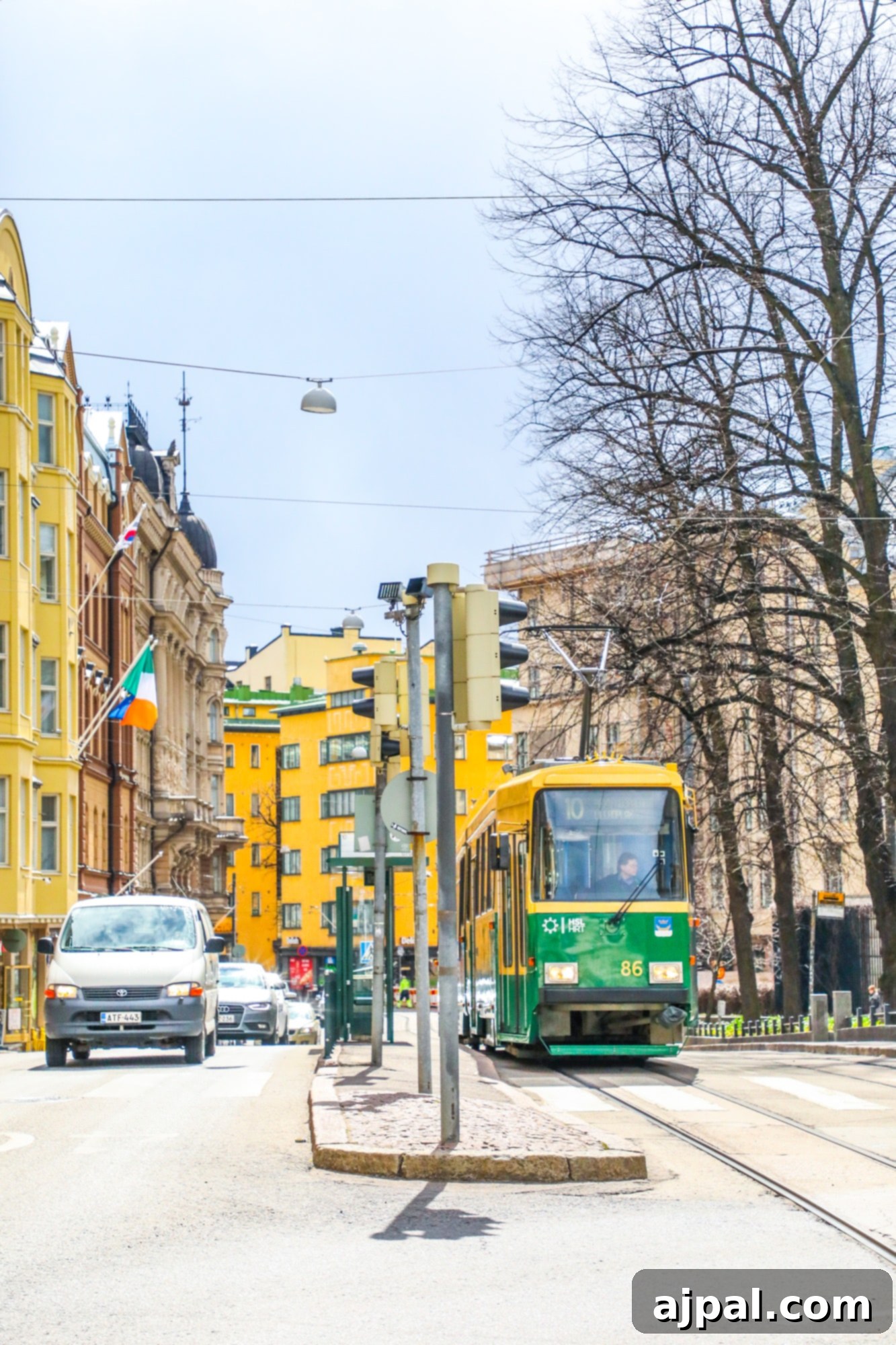 A vibrant green and yellow tram navigating the charming streets of Helsinki, a popular mode of city transport.