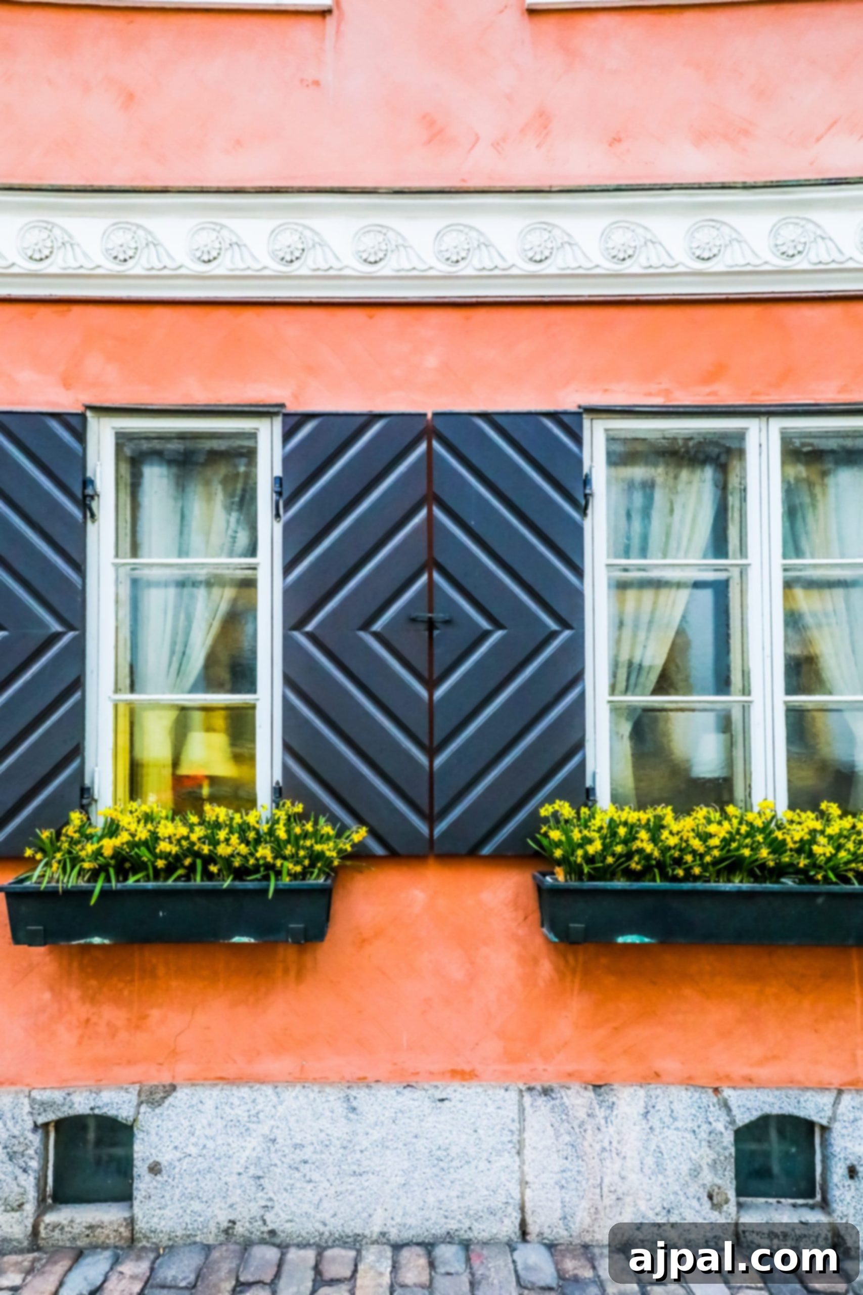 A charming pastel-colored building with dark shutters lining a quaint street in Helsinki.