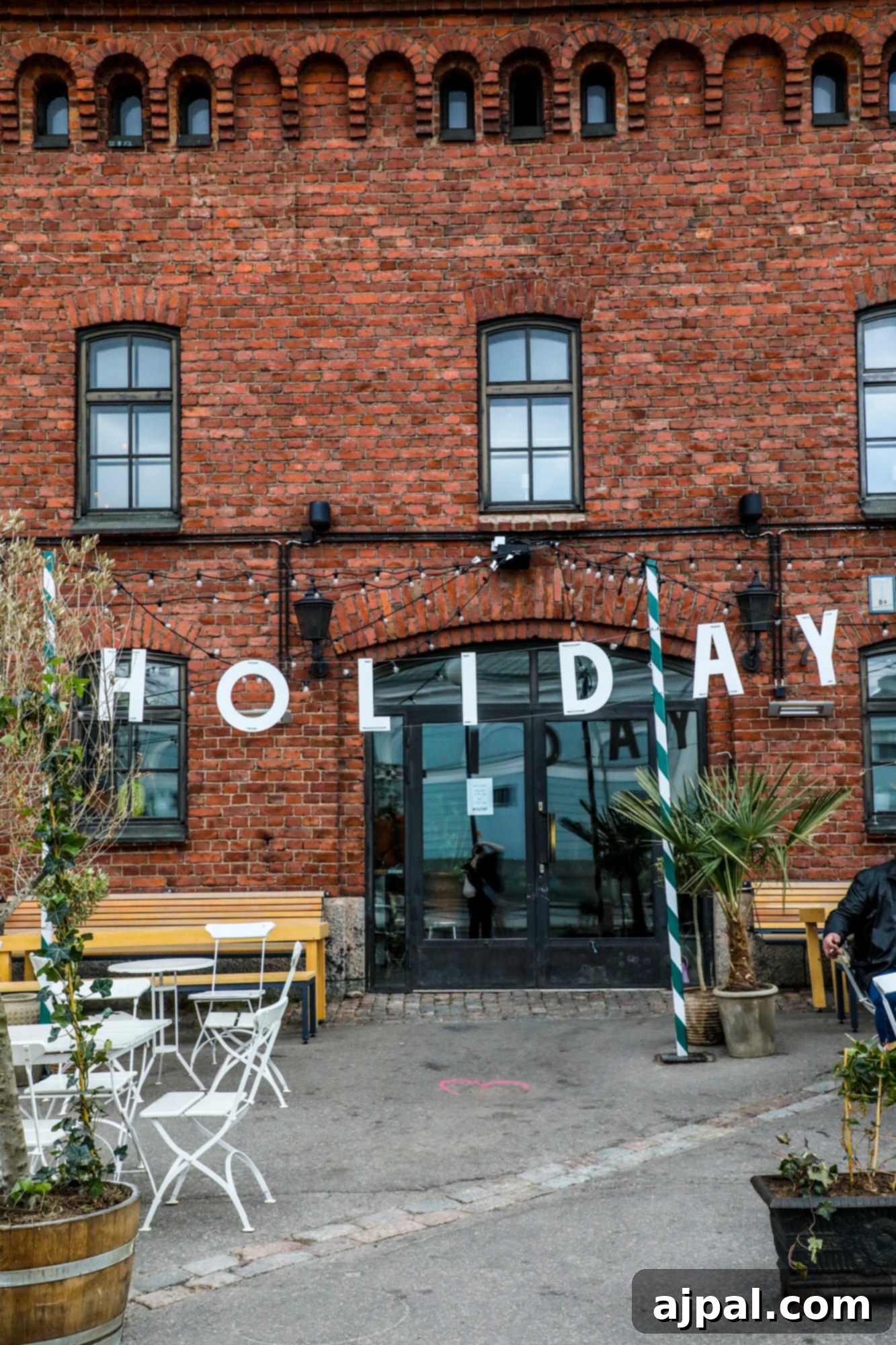 A charming brick building, possibly a restaurant, adorned with festive holiday decorations, stands near the harbor in Helsinki's South Beach area.