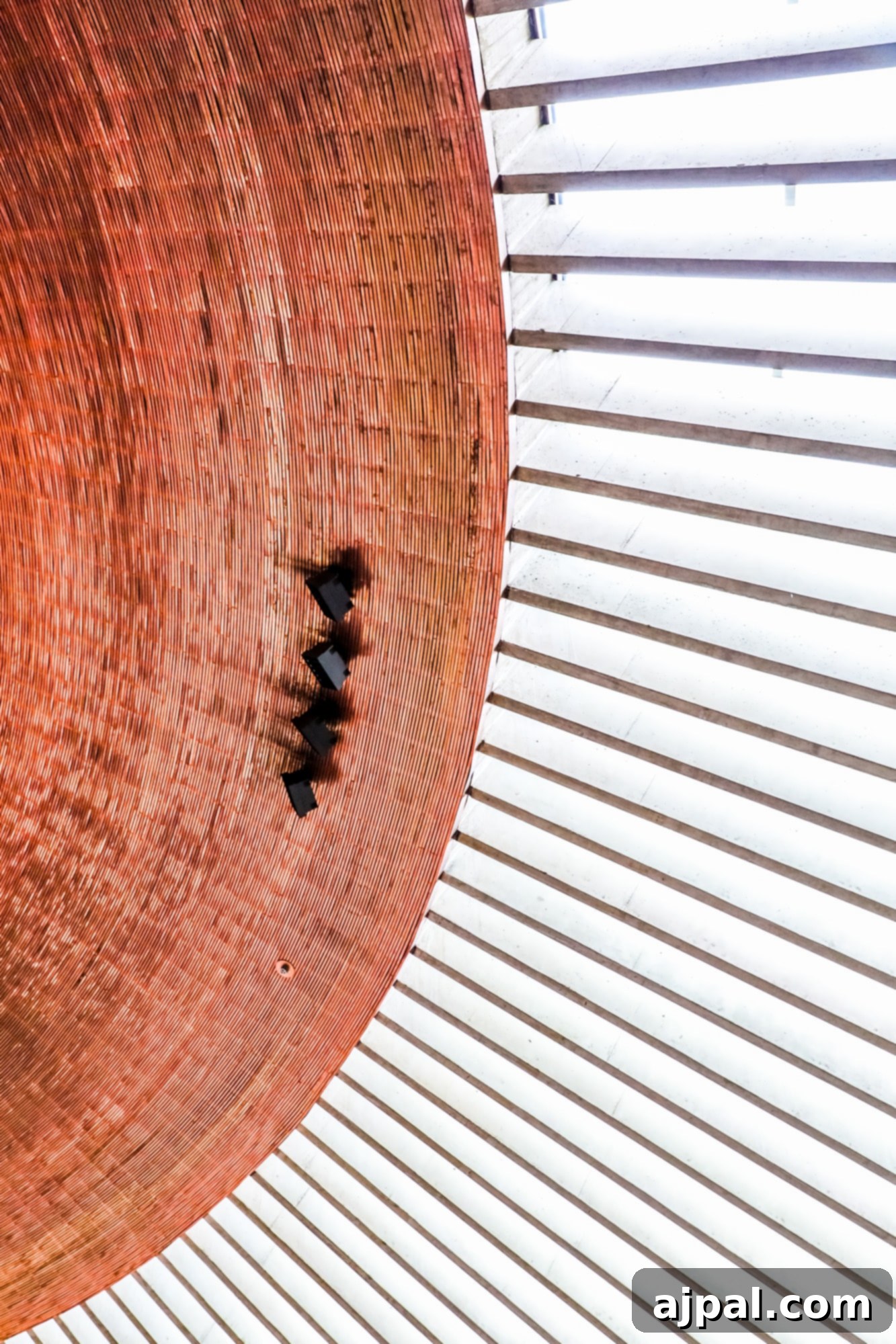 A lone bird rests atop the unique copper dome of Temppeliaukio Church in Helsinki, contrasting with the rock formations.