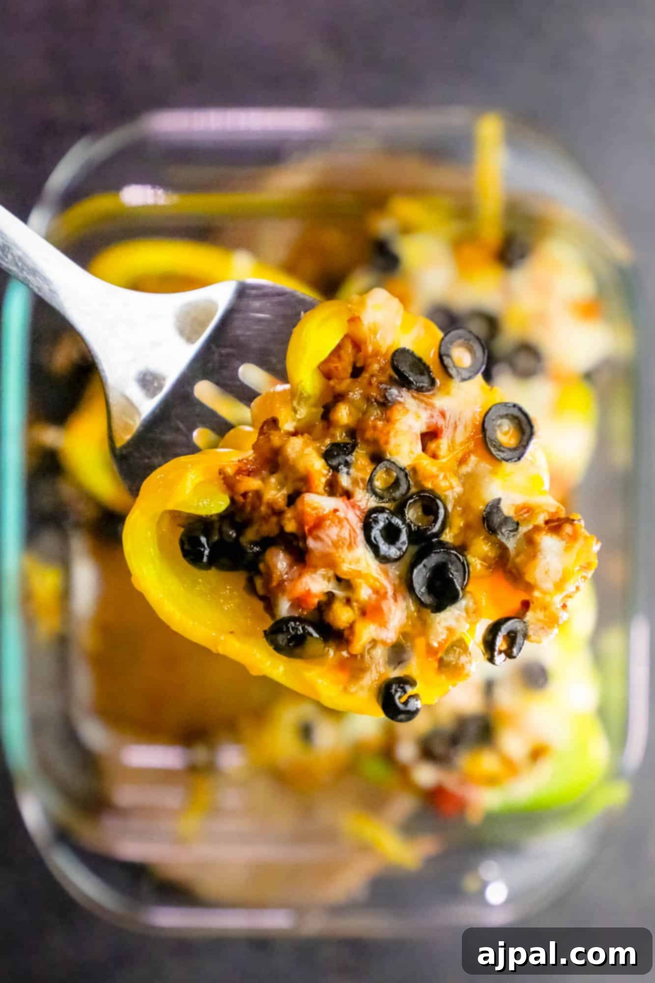 Overview shot of chicken taco stuffed peppers with black olives in a clear glass baking dish, ready for serving or meal prep.