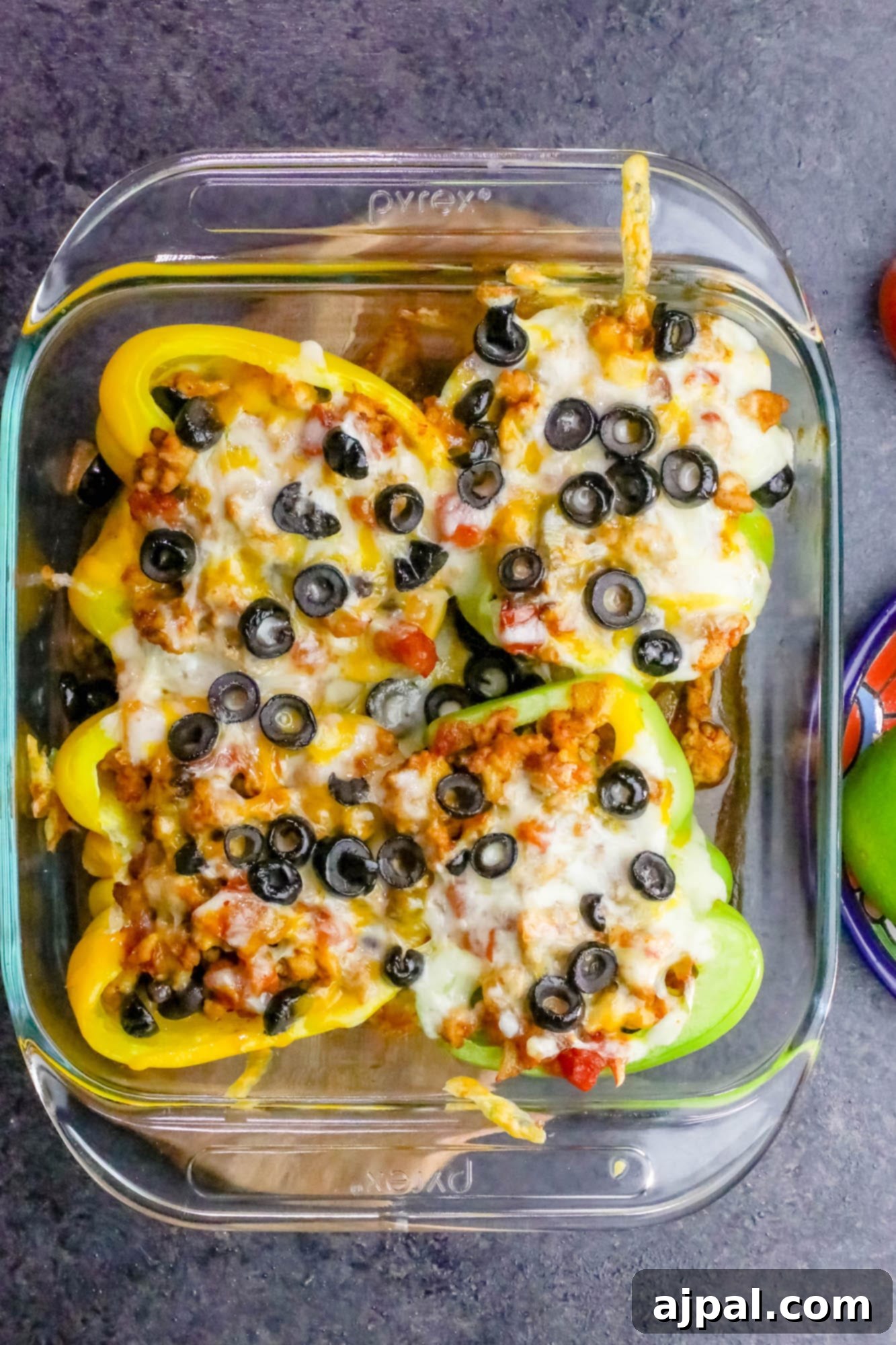 A serving of chicken taco stuffed peppers in a clear glass container, garnished with black olives, perfect for healthy meal prep.