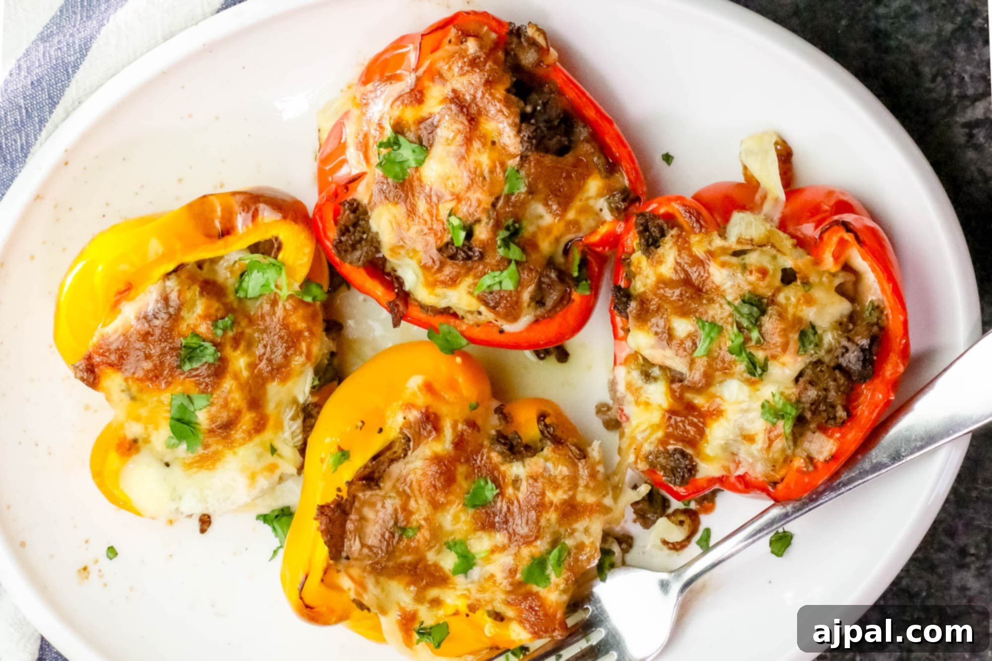 Loaded Cheesesteak Stuffed Peppers 3 Close-up of a baked Philly Cheesesteak Stuffed Pepper on a white plate, showing the melted cheese and juicy filling.
