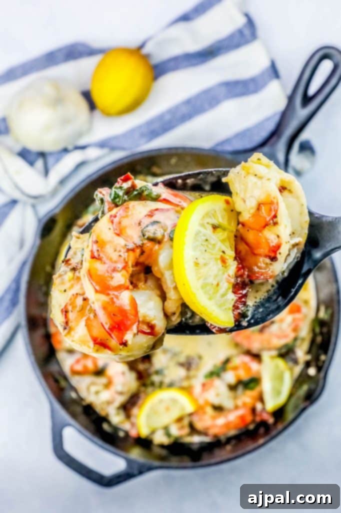 Delicious creamy shrimp Florentine skillet with a spoon, garnished with fresh lemon slices and a hint of butter