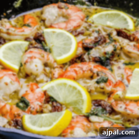 Creamy shrimp in a skillet with lemon slices and spinach, an enticing presentation.