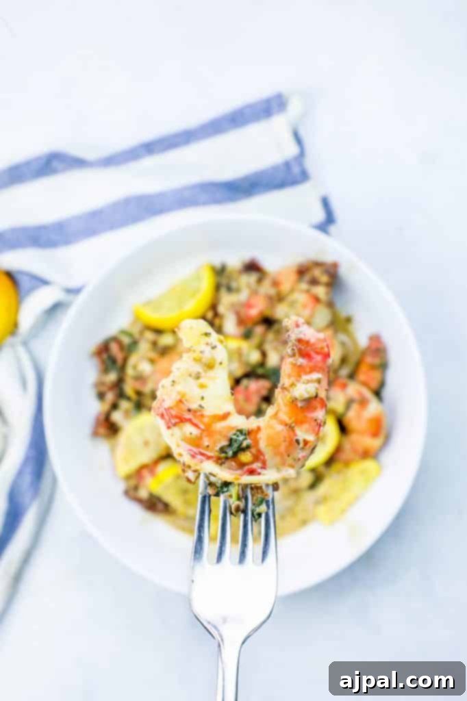 A fork lifts a succulent piece of shrimp from a creamy Florentine skillet, garnished with fresh lemon.