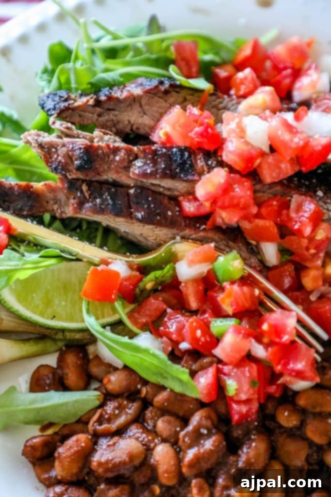 A beautifully grilled flank steak with vibrant lime wedges, ready to be served on a white plate alongside fresh ingredients, showcasing its spicy and zesty appeal.