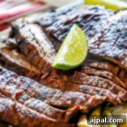 Spicy grilled flank steak with lime served on a white plate.