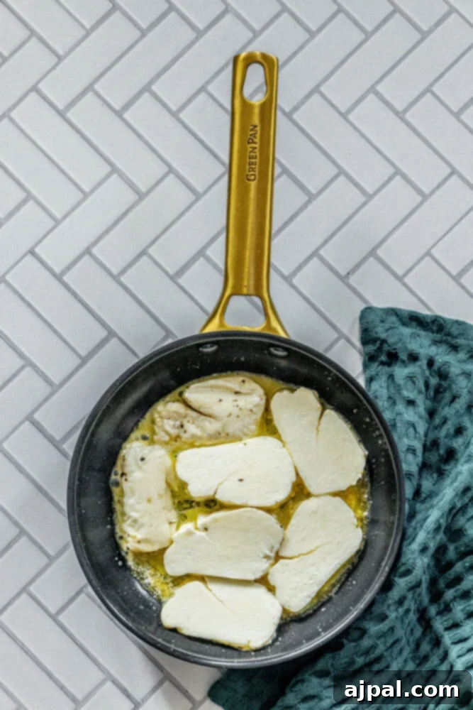 Greek Pan Fried Halloumi Recipe 6 Slices of halloumi cheese gently frying in a pan, beginning to develop a golden crust.