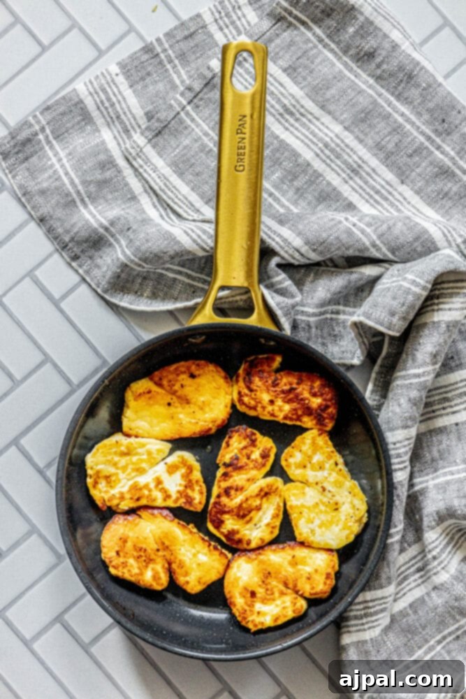 Greek Pan Fried Halloumi Recipe 7 Lightly browned slices of halloumi cheese sizzling in a pan, showcasing their delicious caramelization.