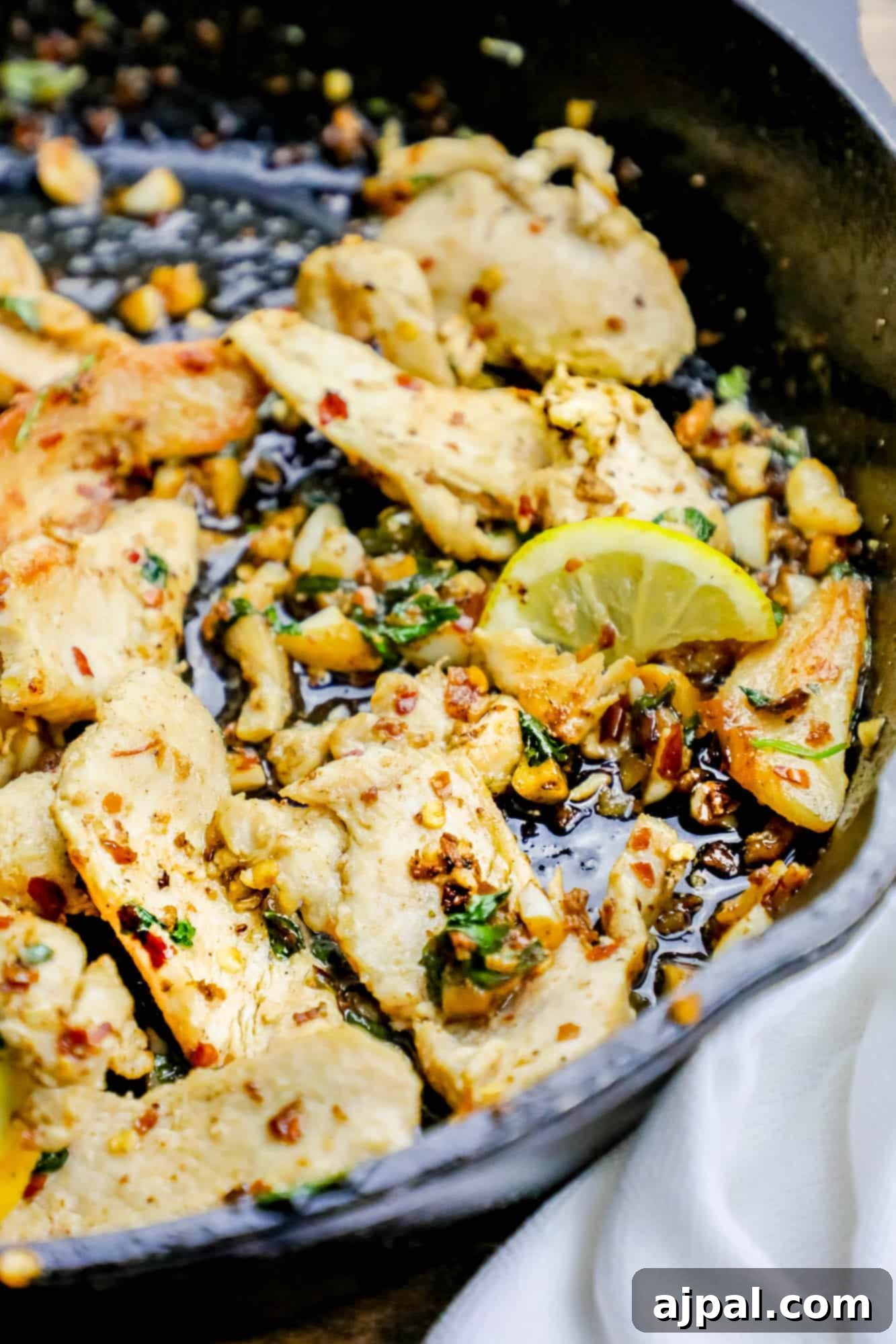 Perfectly pan-fried chicken tenders with lemon slices and red pepper flakes, ready to be served from a skillet.