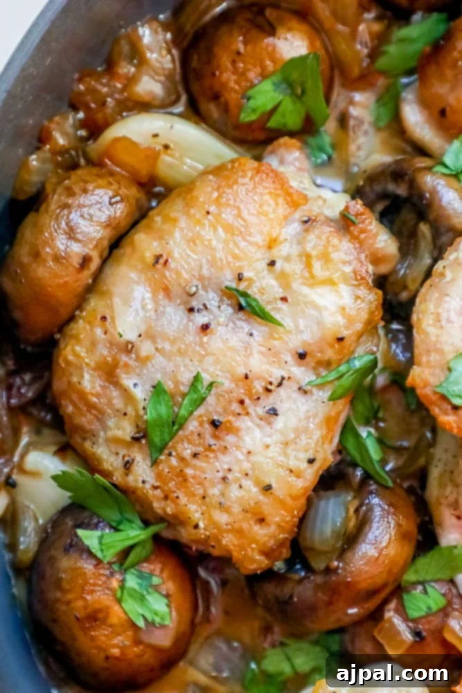 Quick One Pot Garlic Butter Chicken Thighs and Mushrooms 2 Close-up of crispy, golden-brown chicken thighs and sautéed mushrooms glistening in a vibrant garlic butter sauce, served fresh from a single pan.